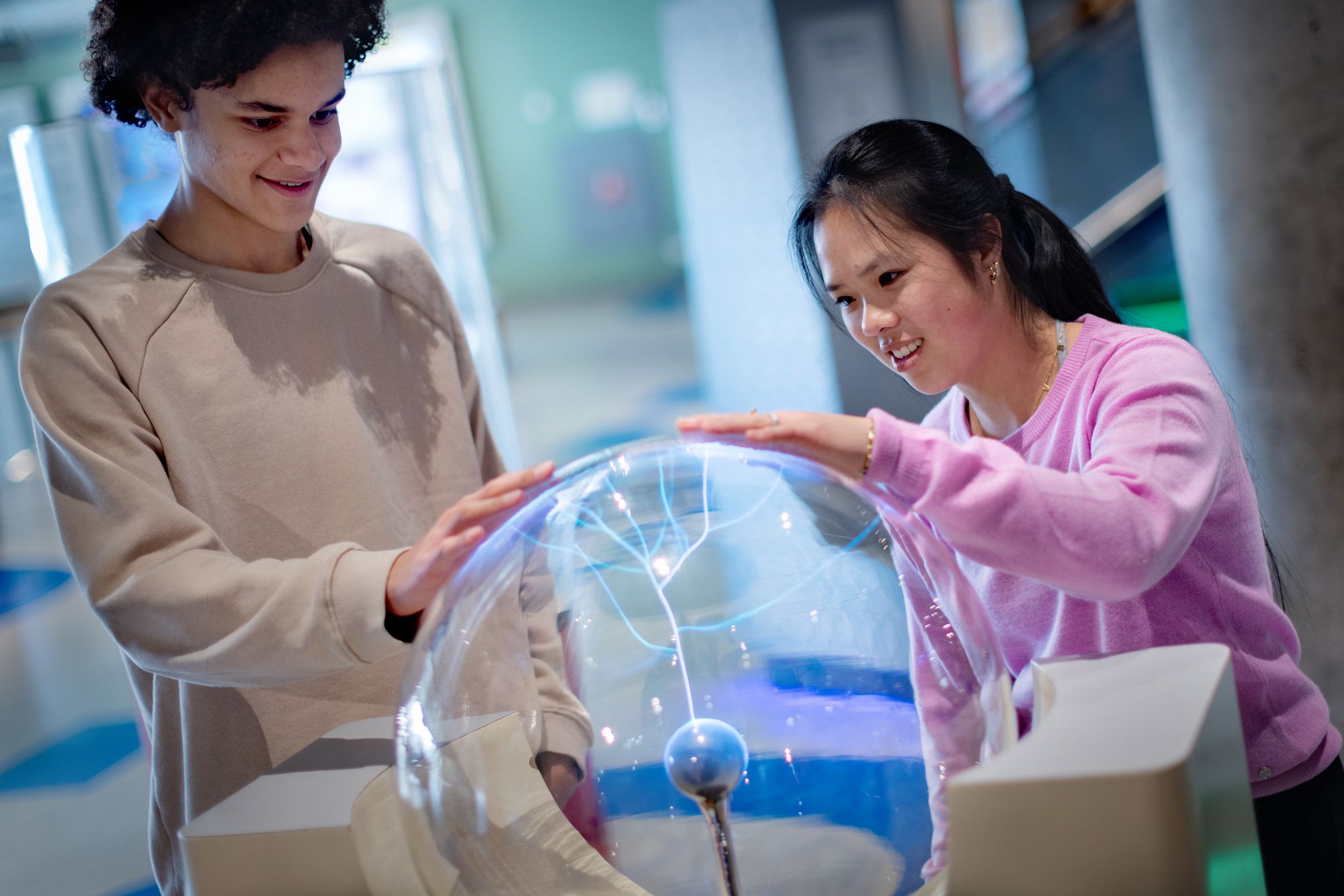 Een jongen en een meisje hebben een hand op de teslabol