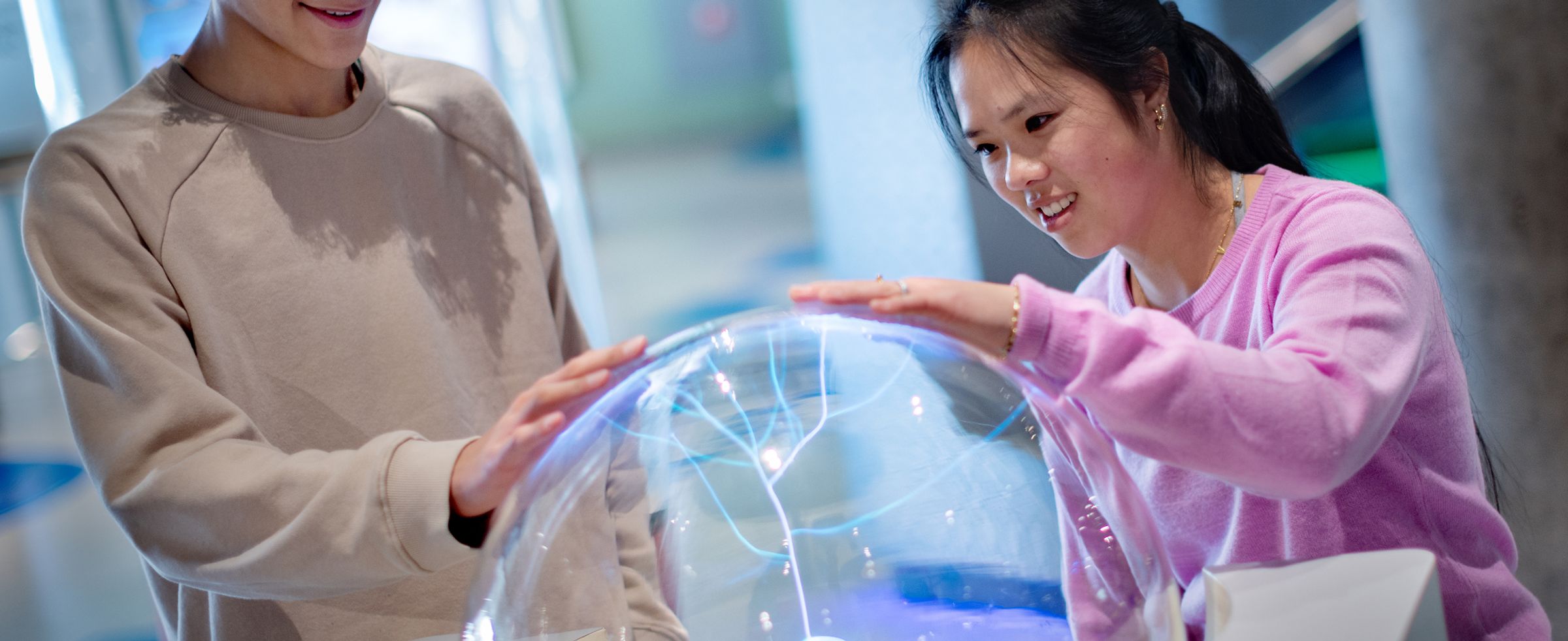 Een jongen en een meisje hebben een hand op de teslabol