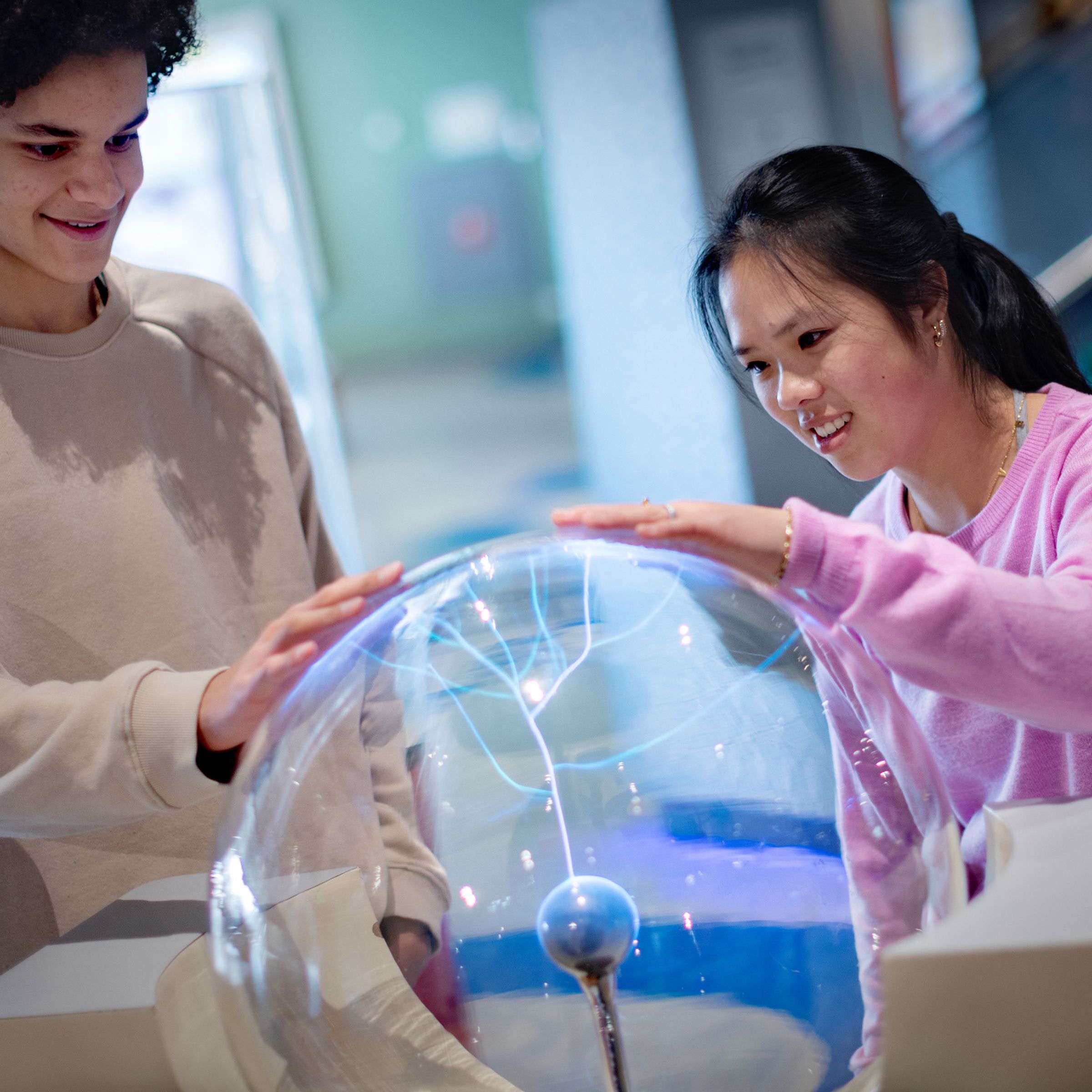 Een jongen en een meisje hebben een hand op de teslabol