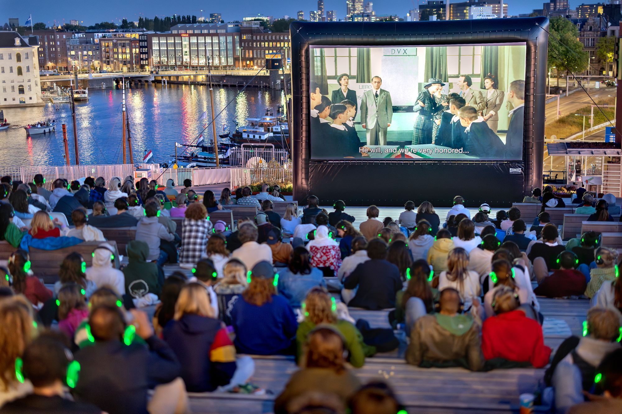 publiek kijkt bij zonsondergang naar groot filmscherm op het dak van NEMO