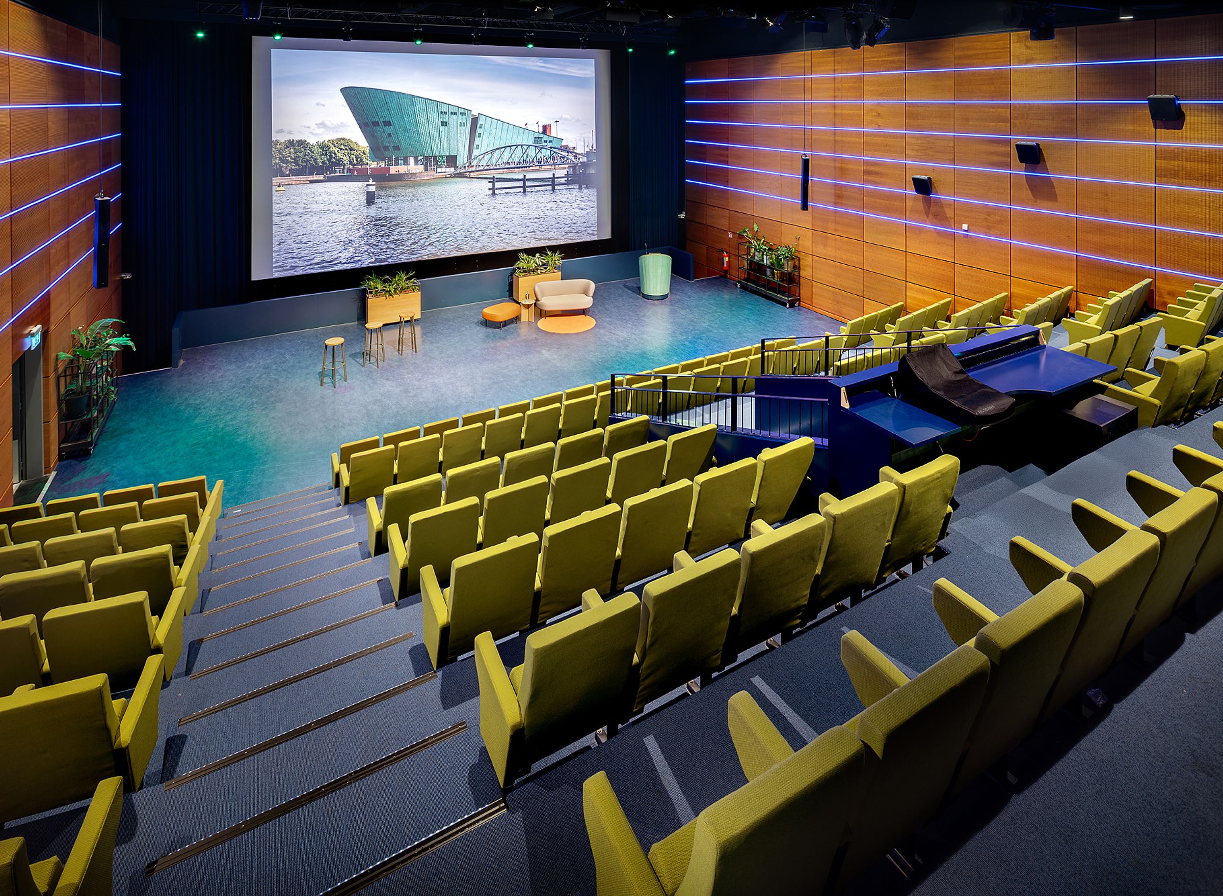 Een grote lege zaal met groene klapstoelen