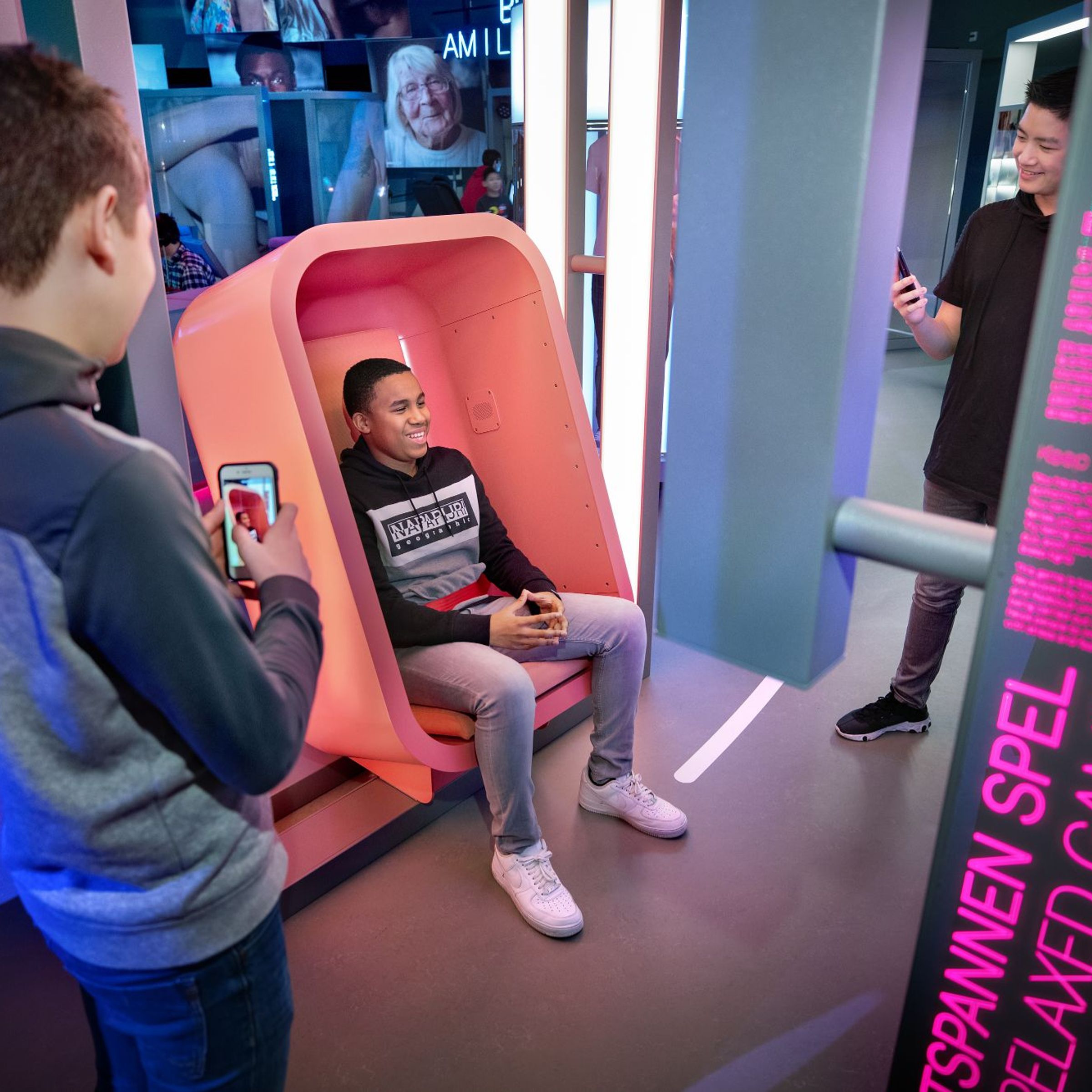 Een jongen filmt een andere jongen die in een stoel zit.