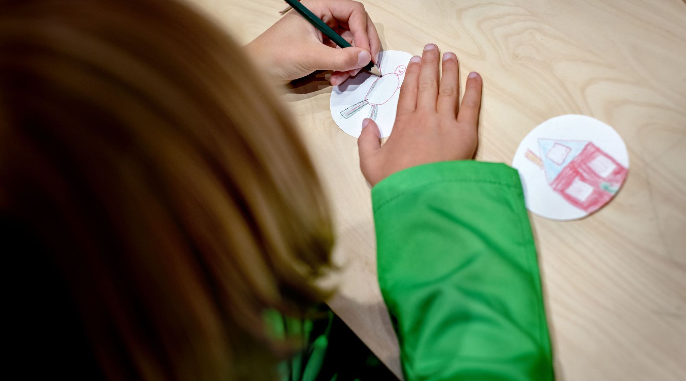 Een meisje maakt een tekening op een rondje papier