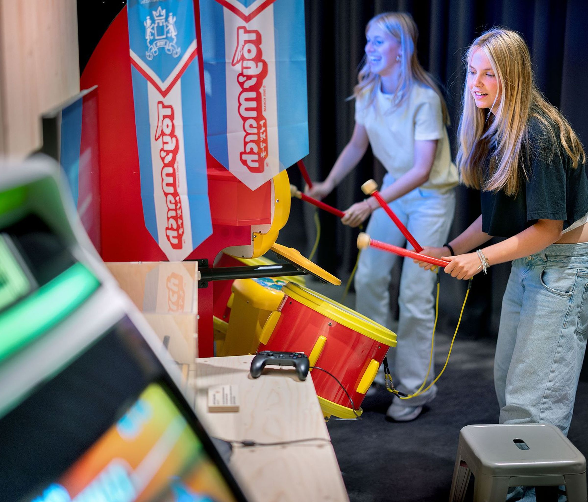 Twee meiden trommelen op een arcadekast