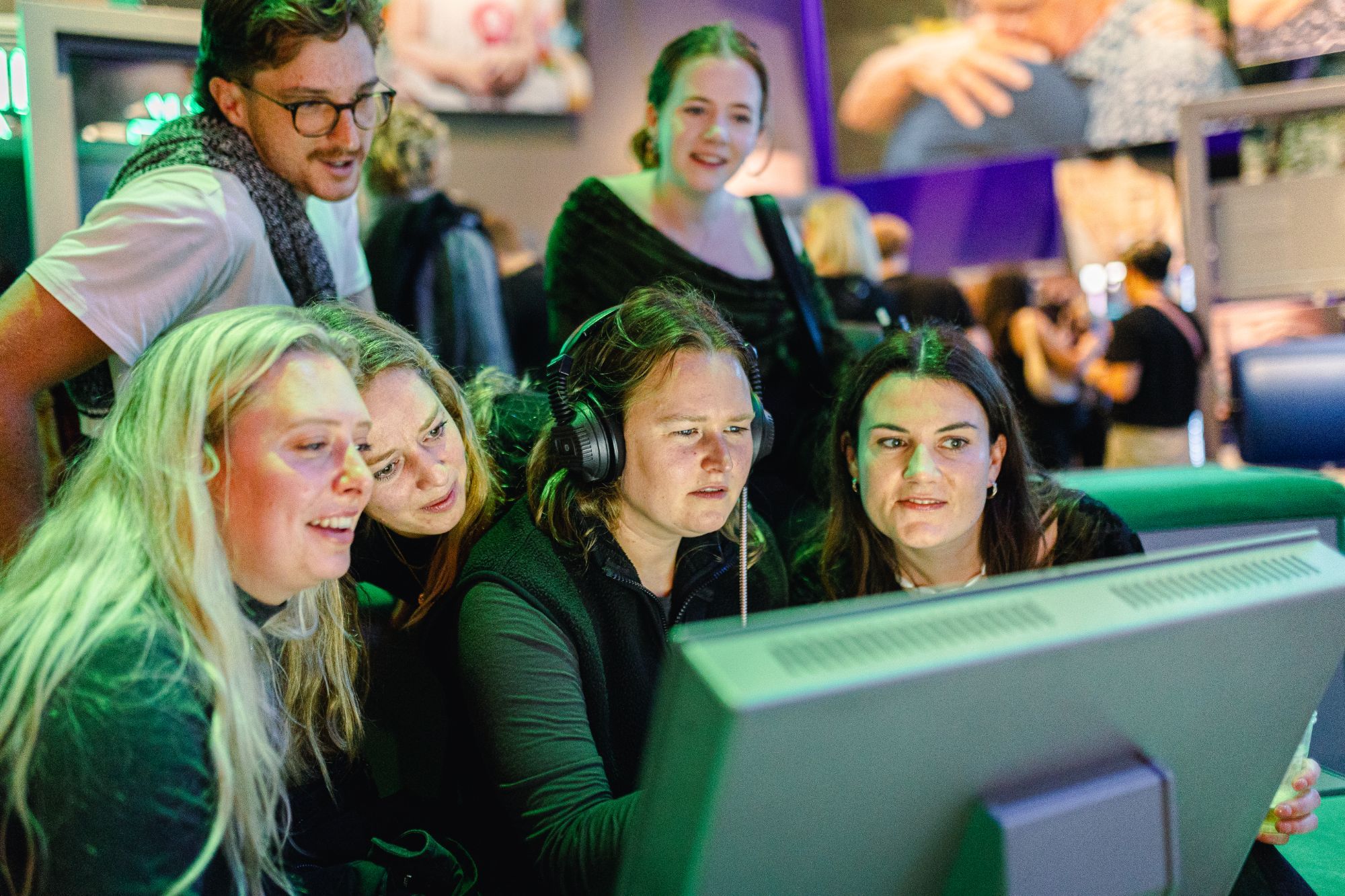 Een lachende groep mensen kijkt naar een scherm