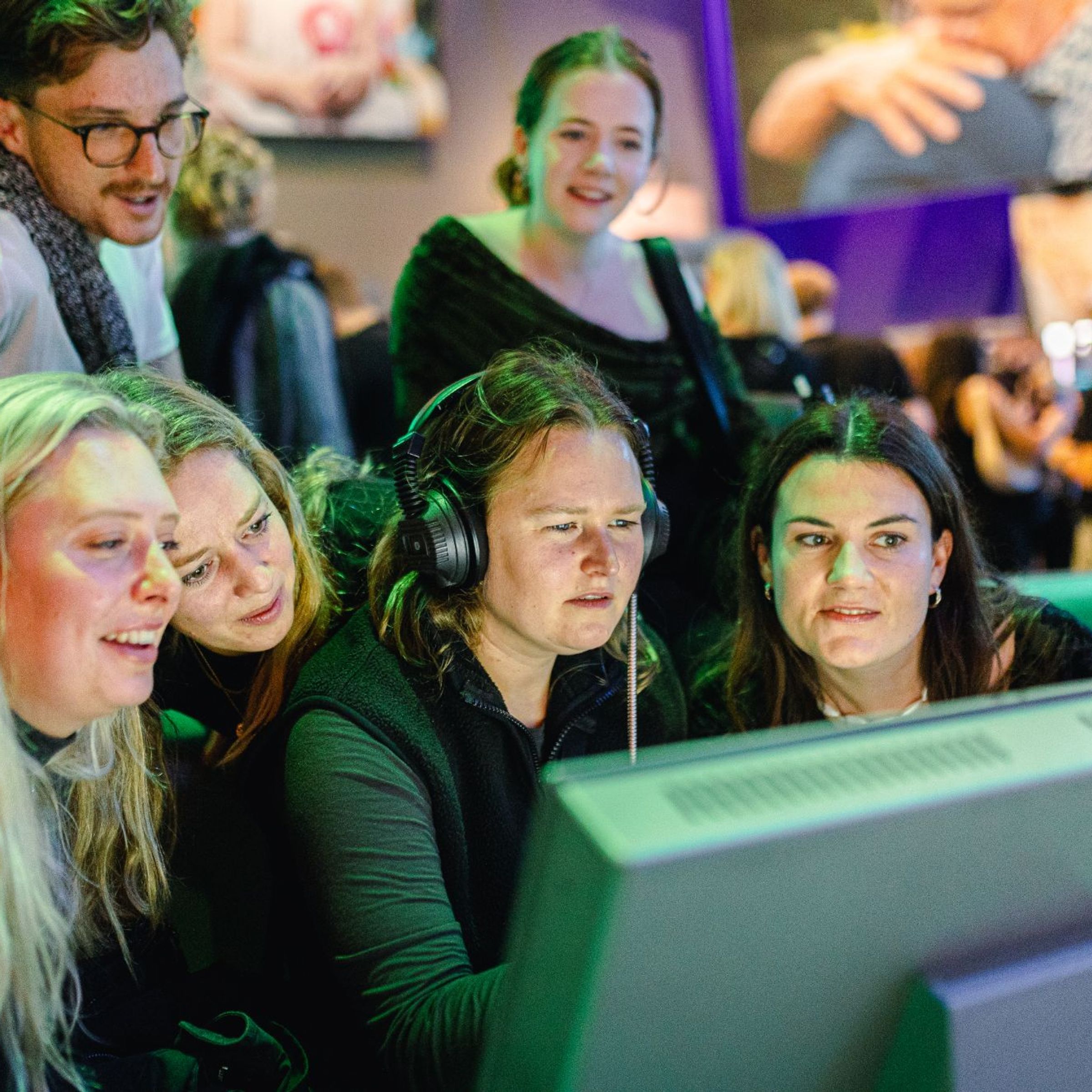 Een lachende groep mensen kijkt naar een scherm