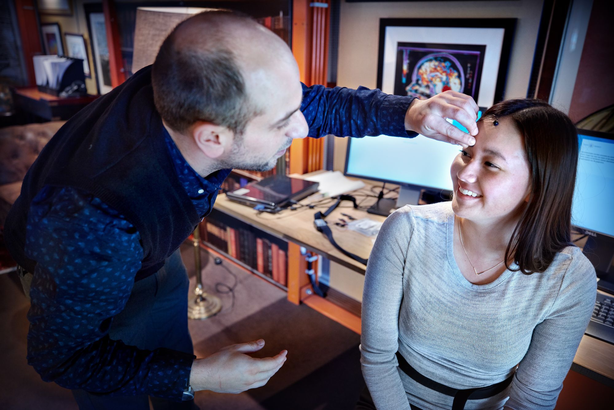 A man is sticking a sensor on the head of a smiling girl