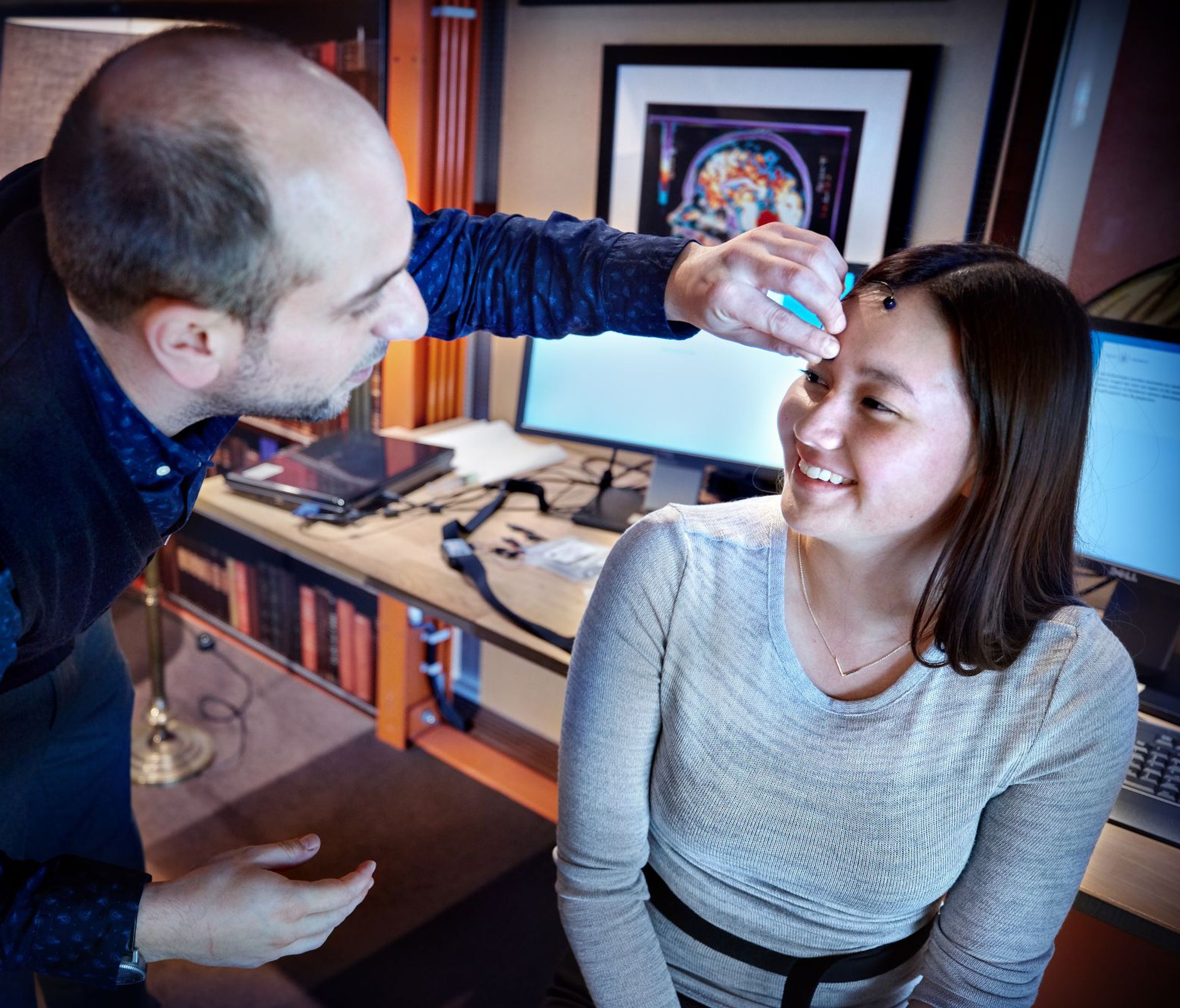 A man is sticking a sensor on the head of a smiling girl