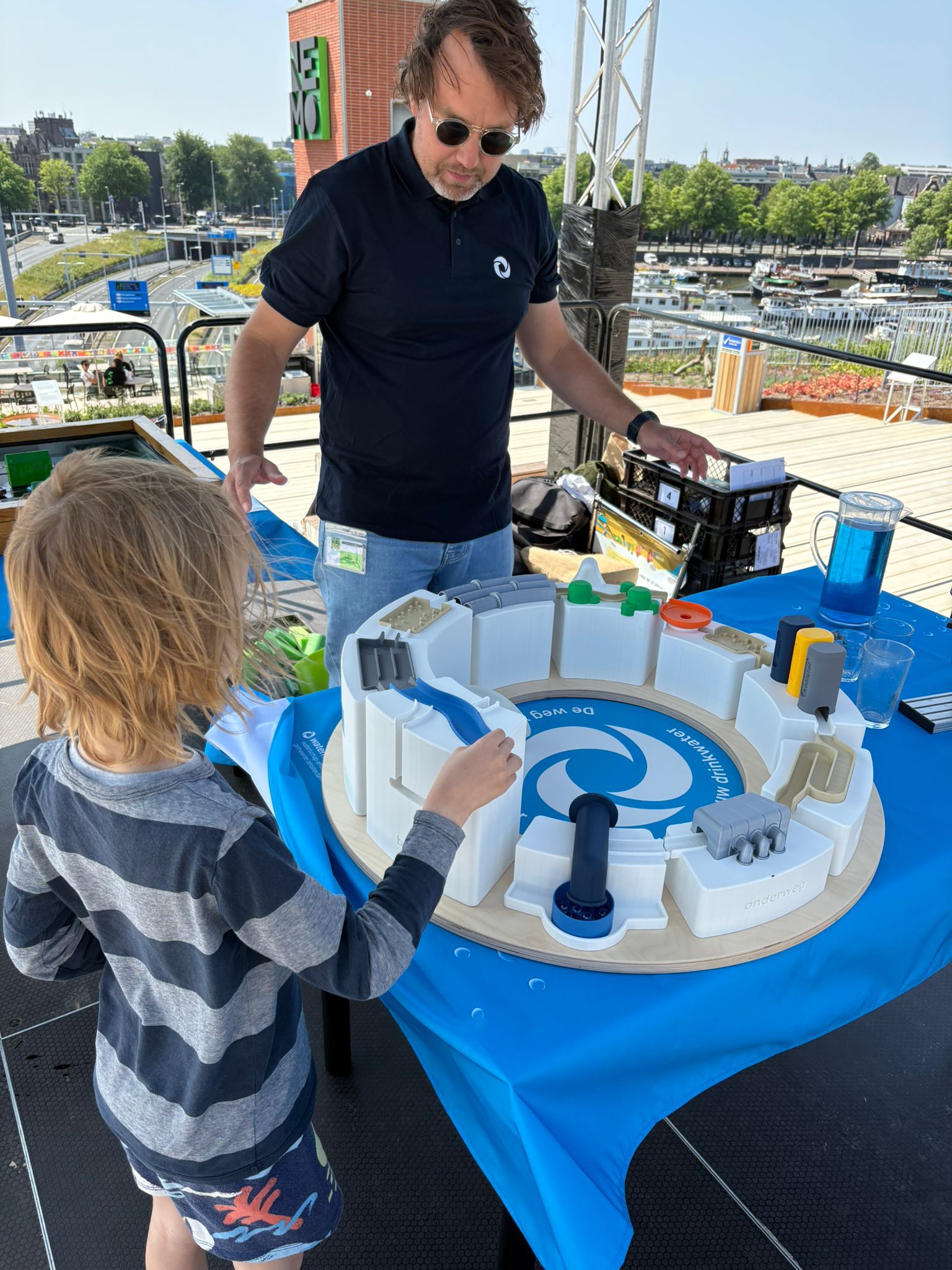 Een man en een kind bij een knikkerbaan met water