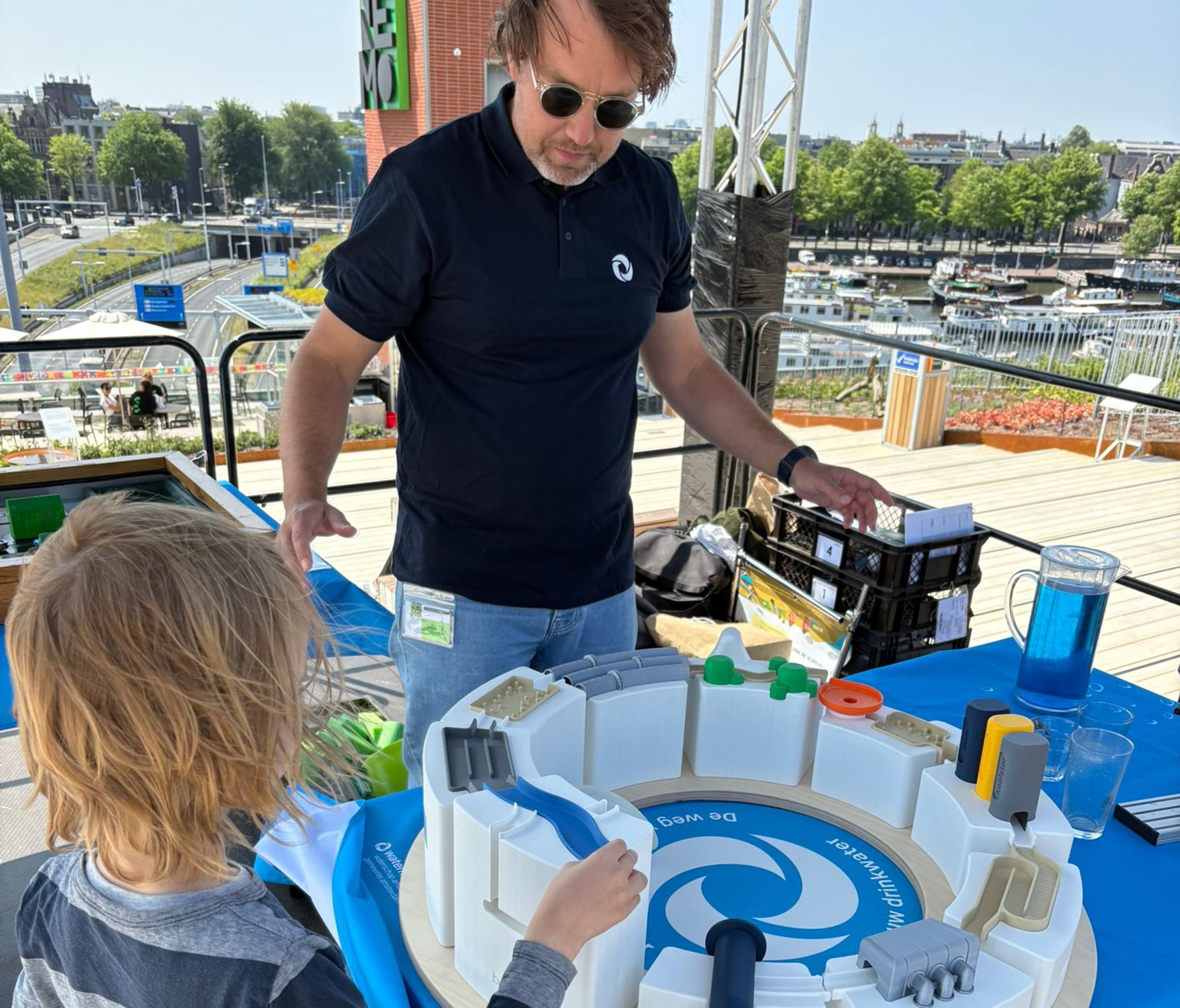 Een man en een kind bij een knikkerbaan met water