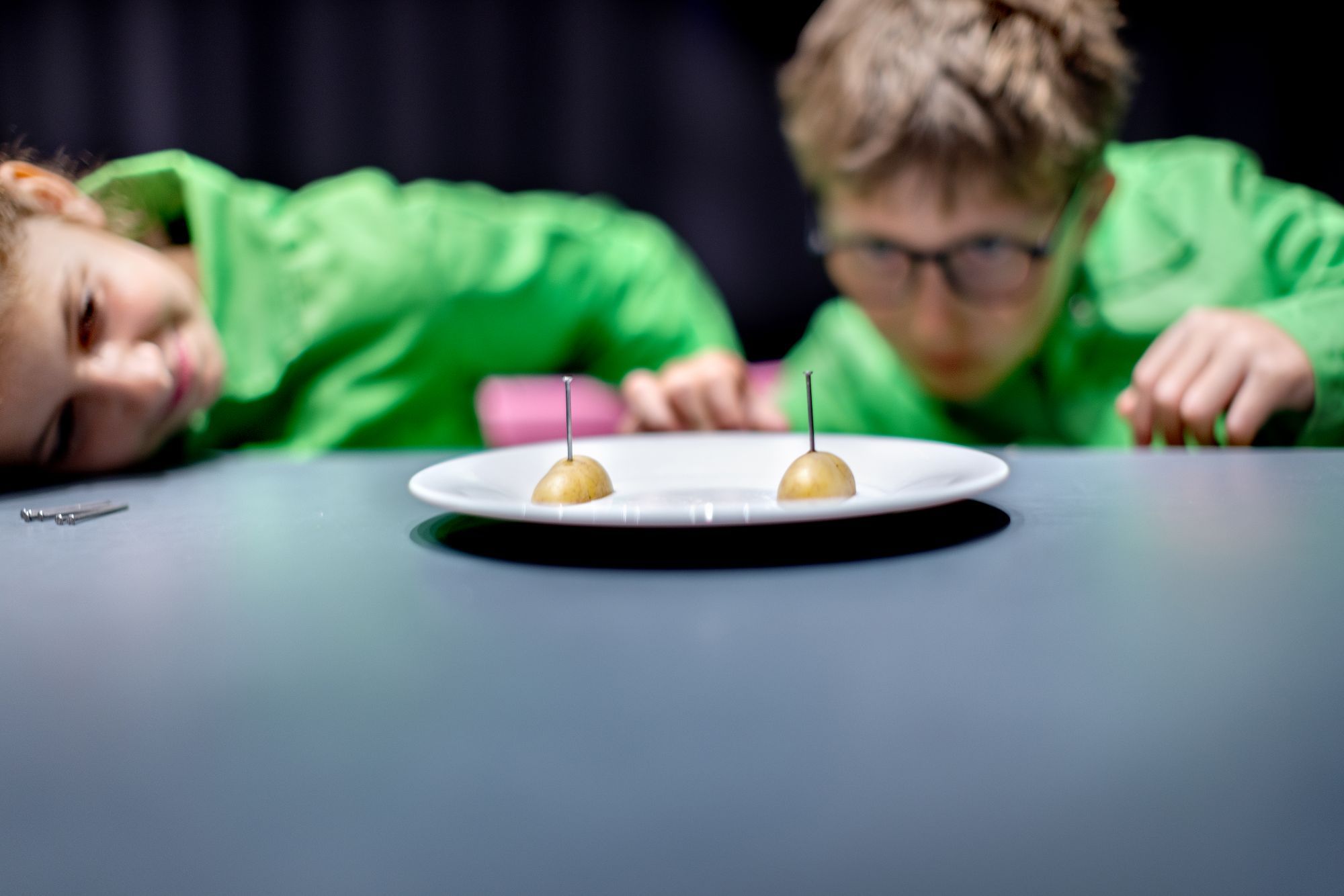 Een bord met twee halve aardappels waarin spijkers zijn gestoken