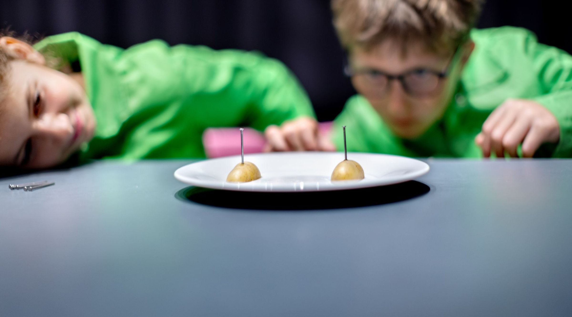 Een bord met twee halve aardappels waarin spijkers zijn gestoken