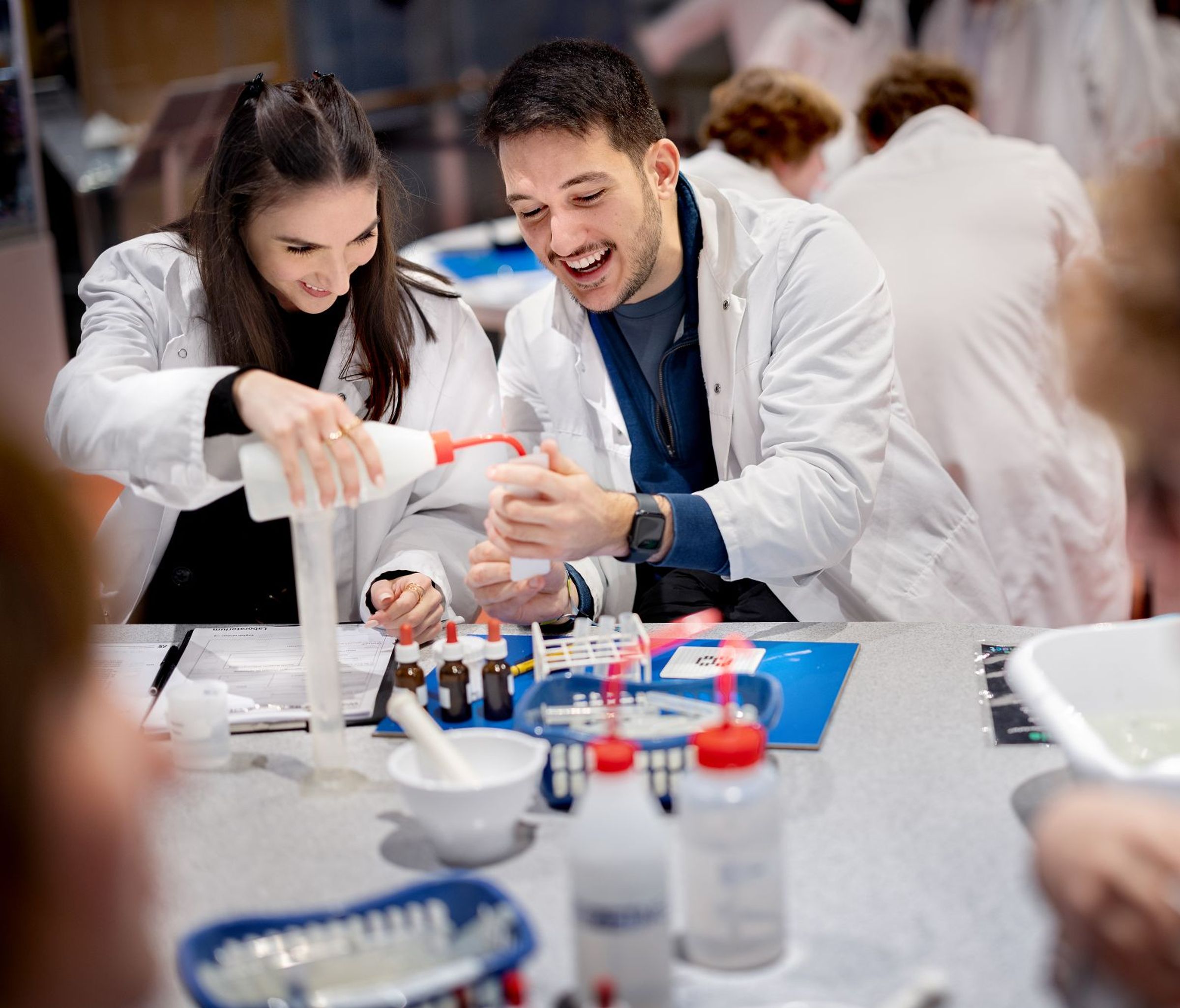 Twee mensen van rond de dertig doen een proefje in het laboratorium.
