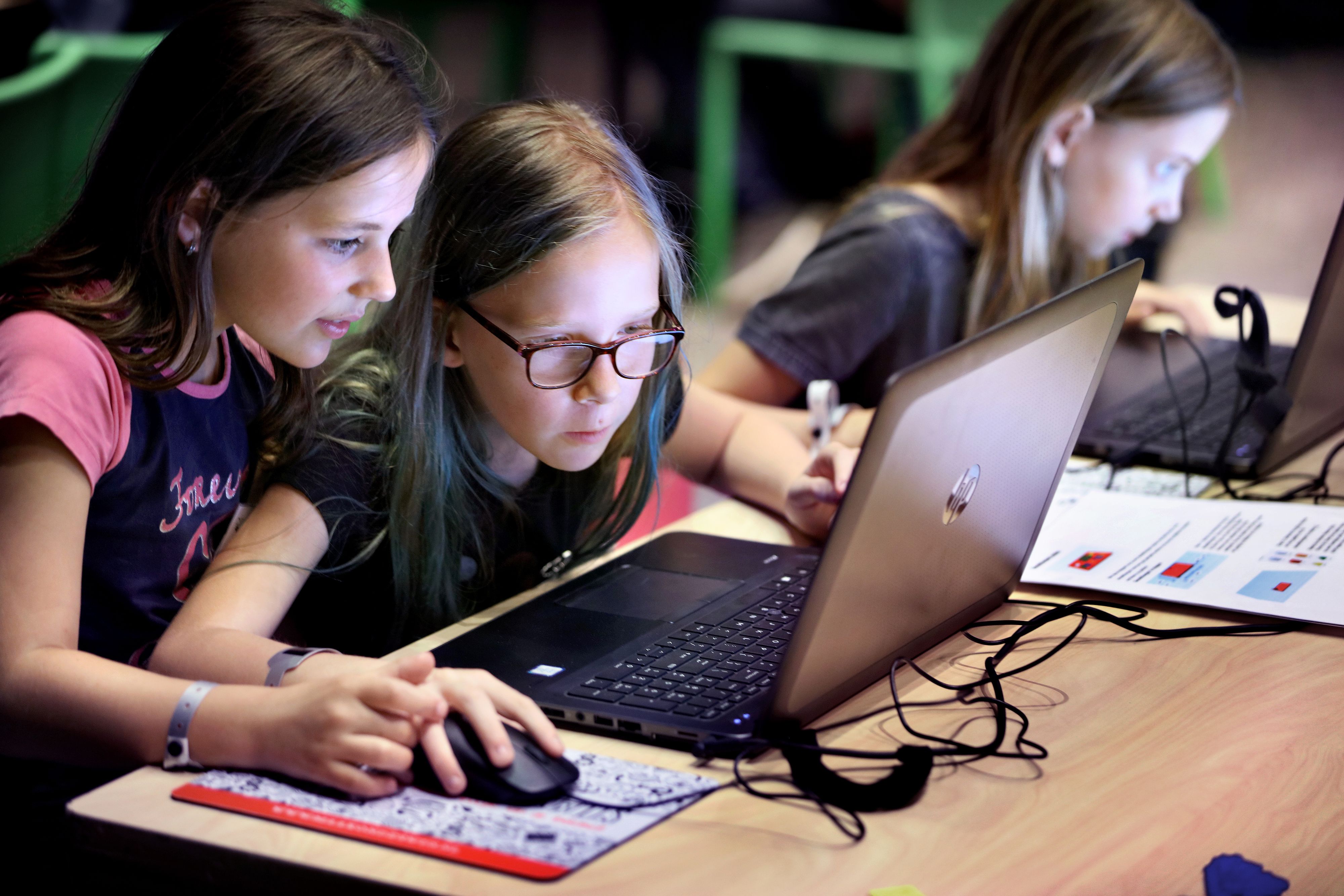 Drie kinderen zitten achter een laptop.