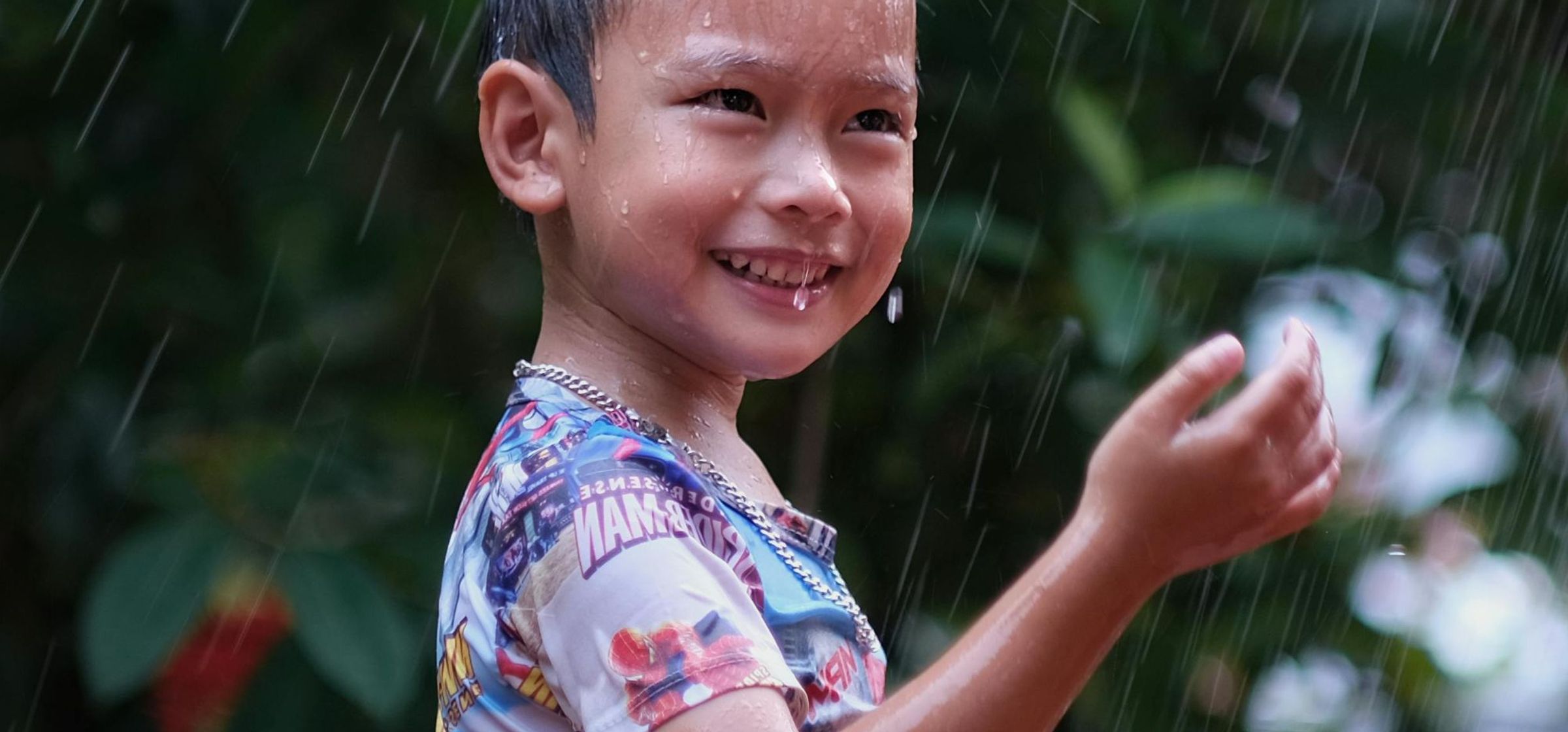 Een jongen lachend in de regen.