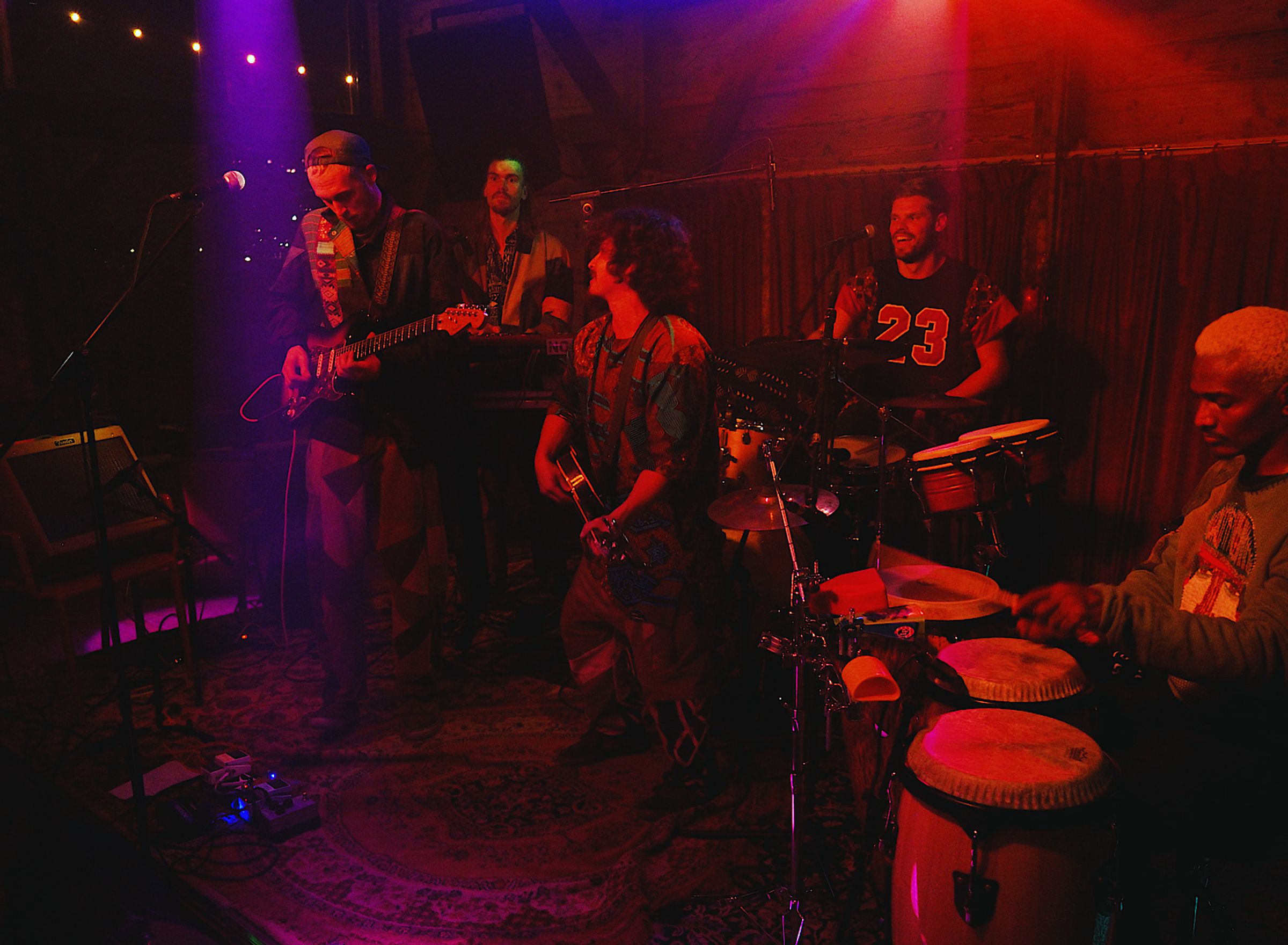 een band speelt in paars en rood licht