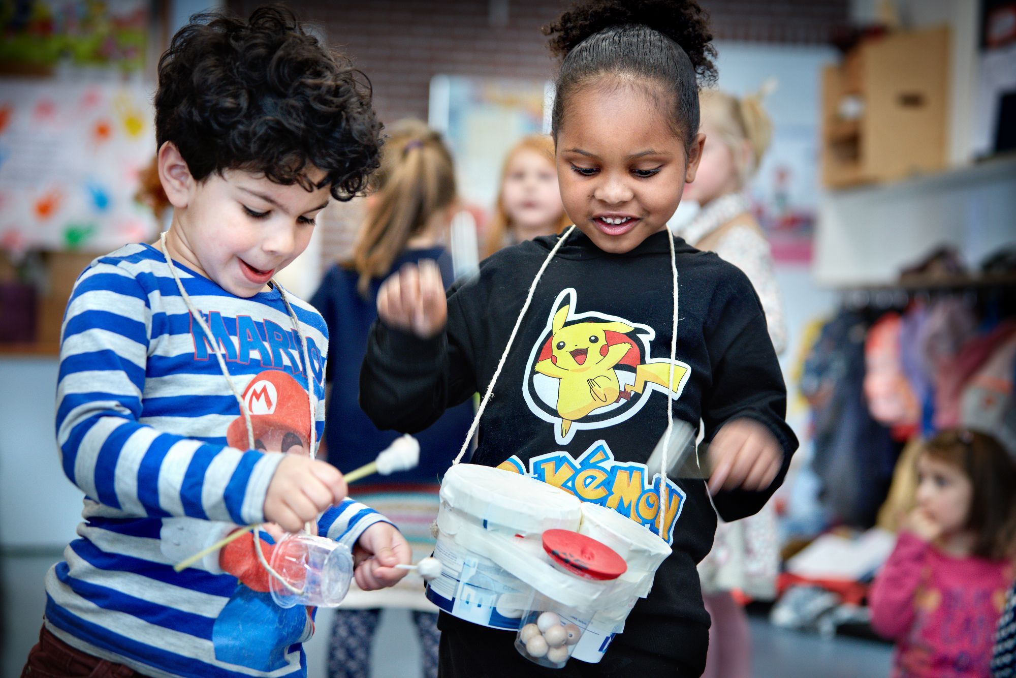 Twee kinderen spelen met drums gemaakt van emmers.