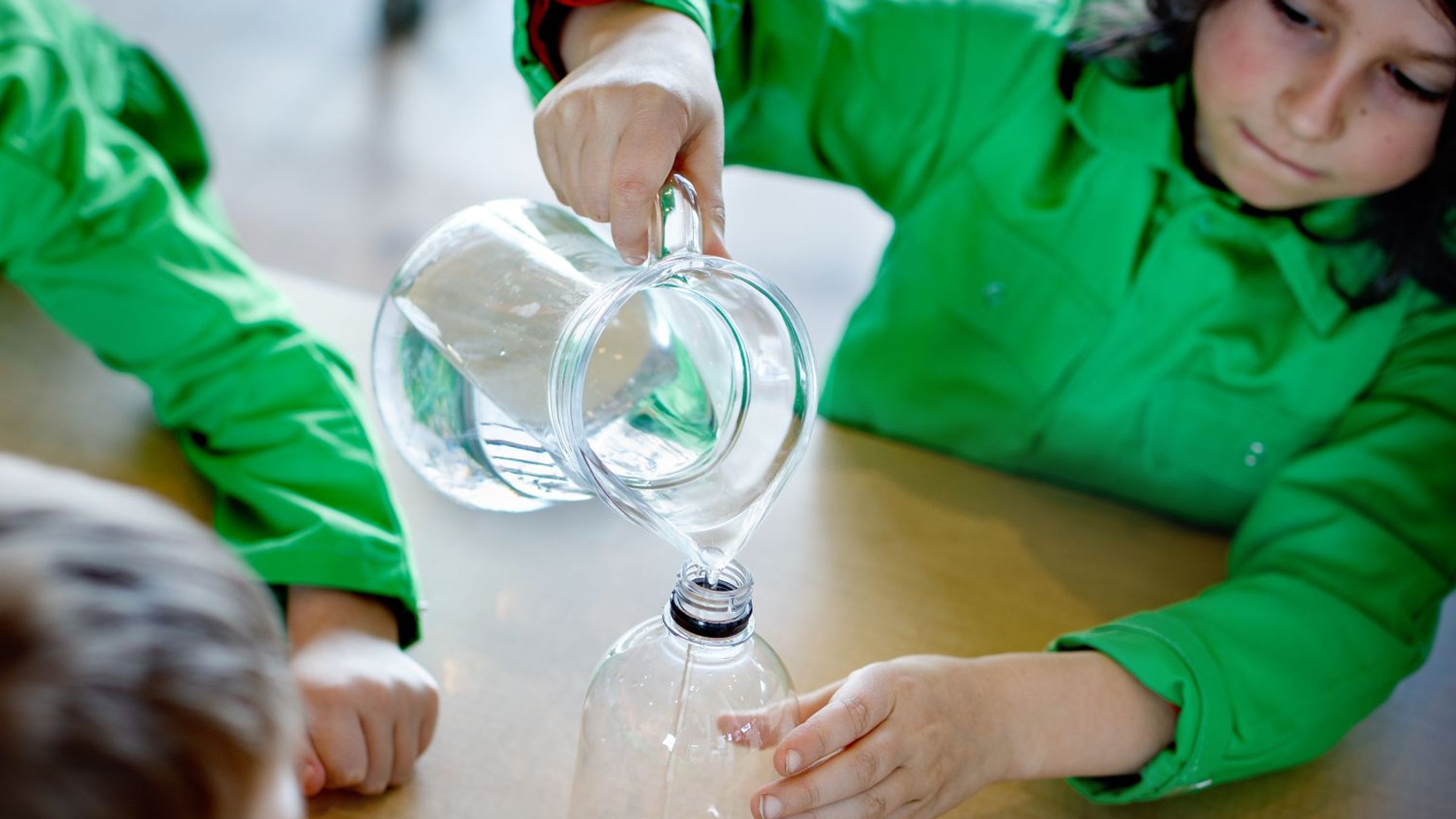 kinderen schenken water in een fles