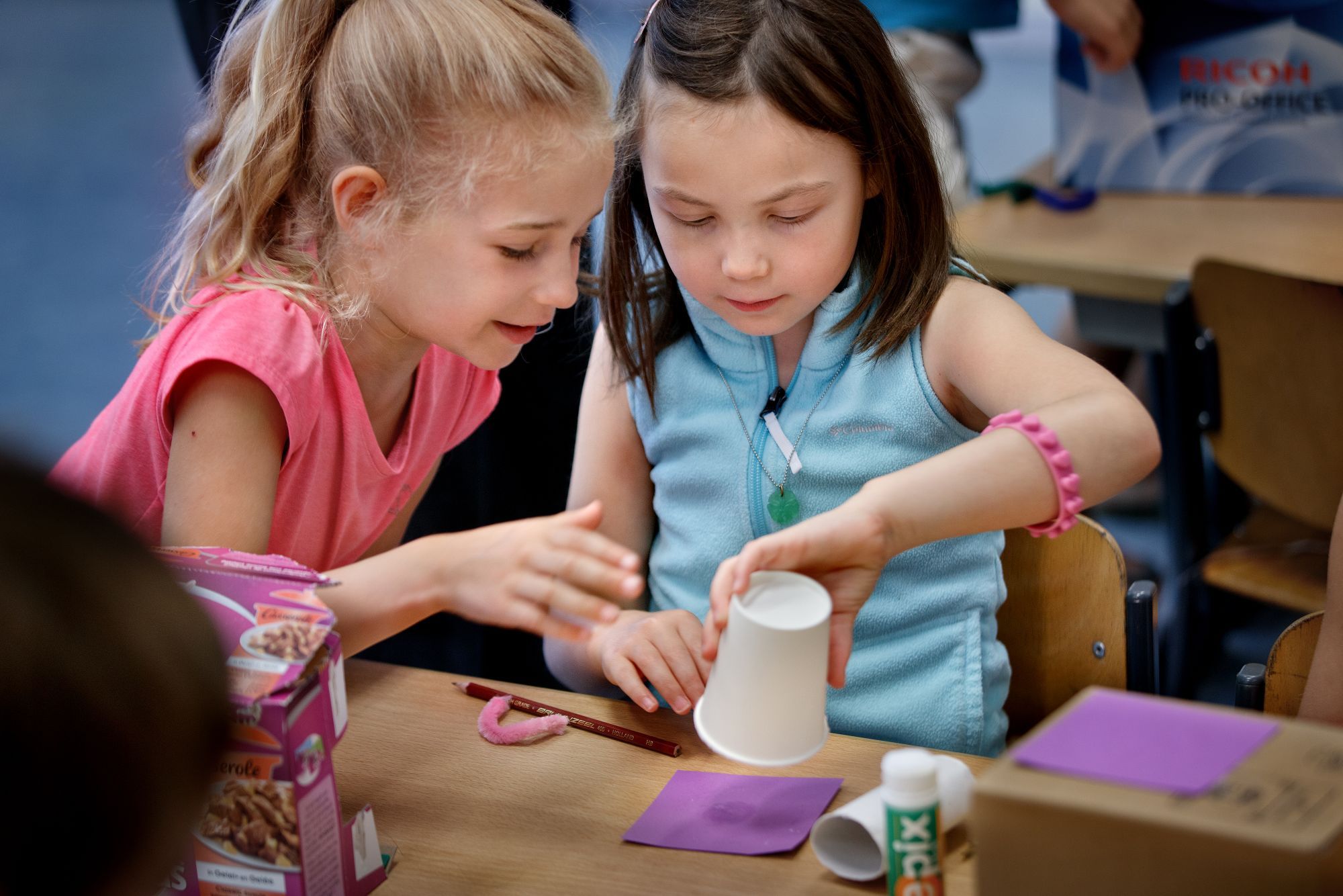 twee meisjes maken iets met een papieren beker