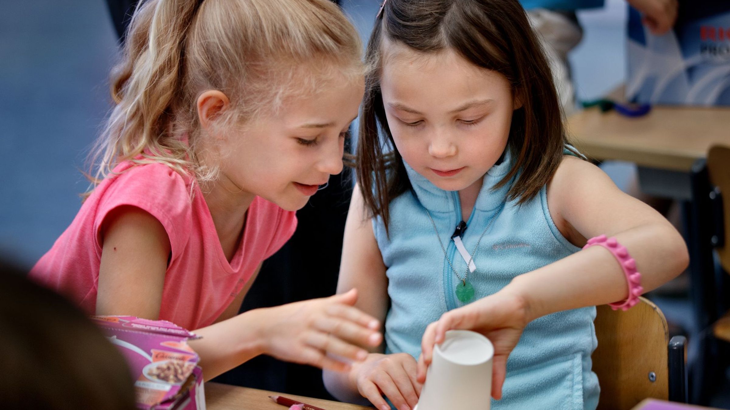 twee meisjes maken iets met een papieren beker