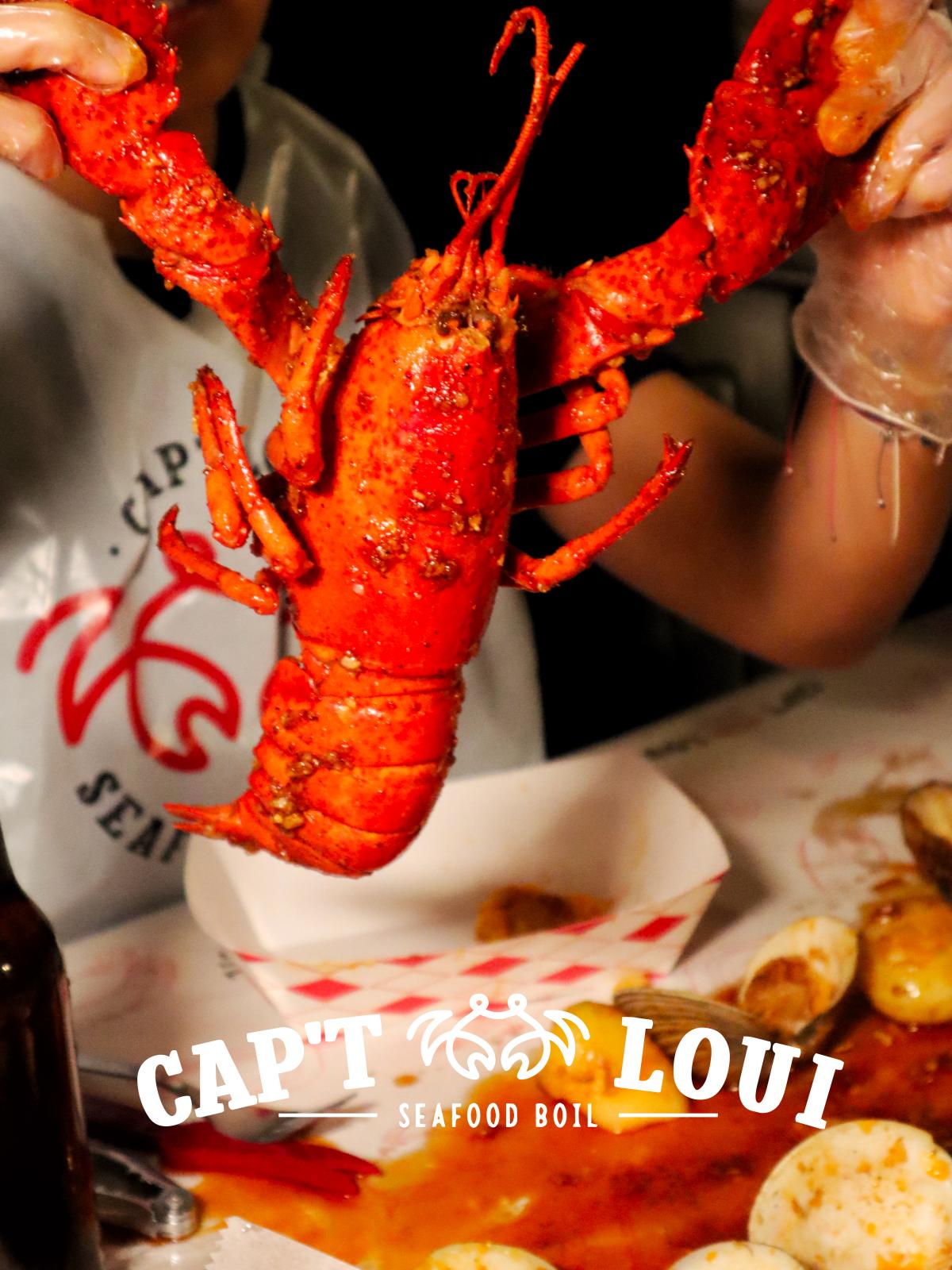 A whole lobster and seafood served on paper in a branded basket.