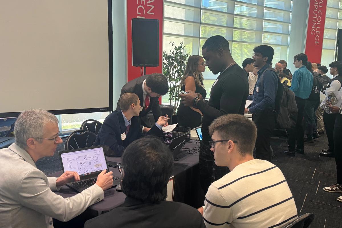 Diverse group of NJIT computer science students collaborating on capstone software engineering projects in a modern workspace