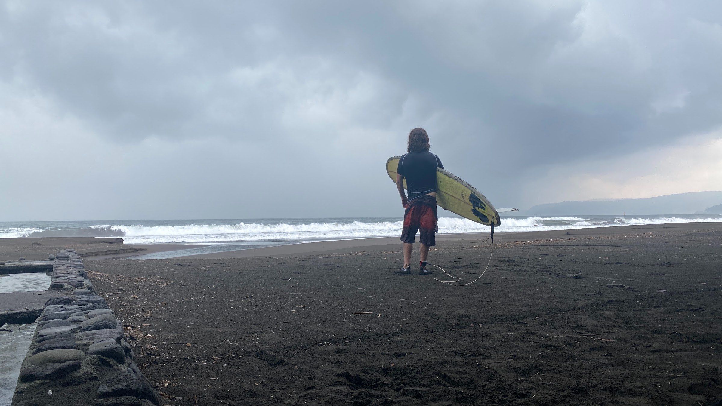 A surfer carrying a board toward the sea