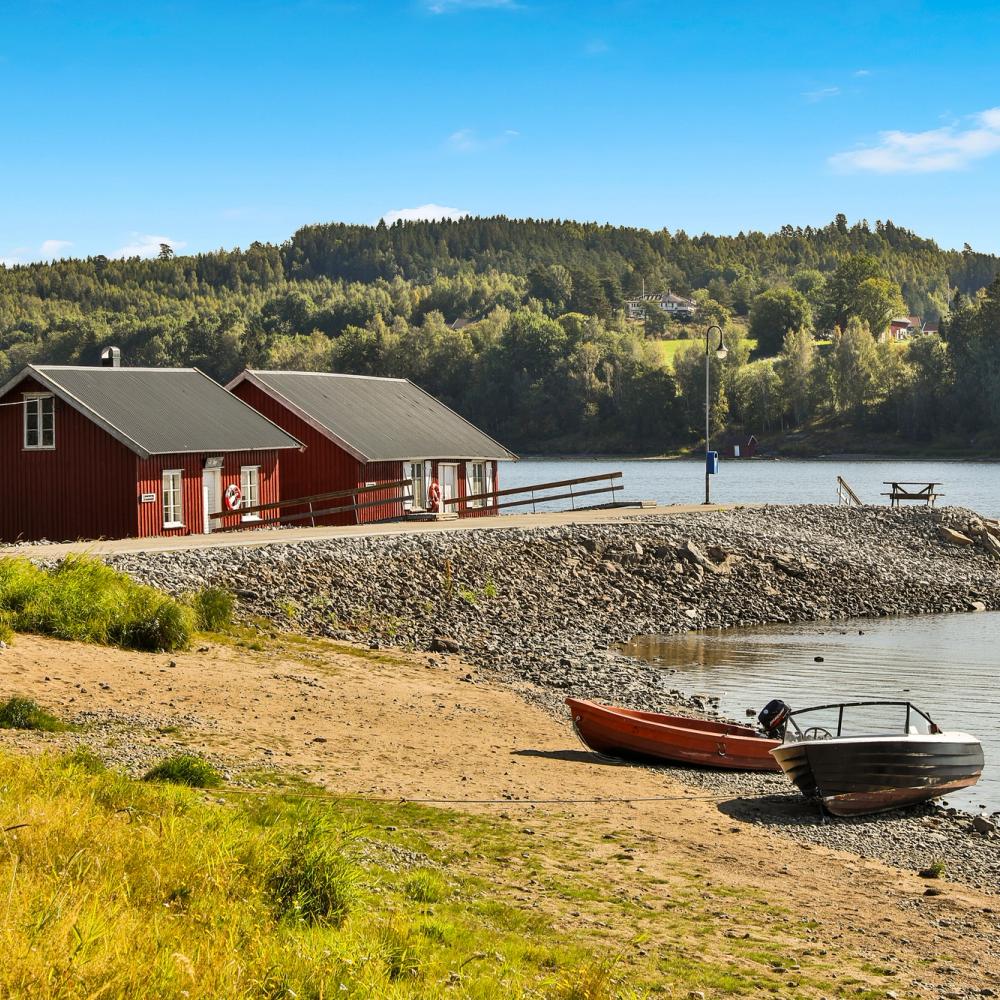 Sjøboder på stranden og to småbåter. Foto.