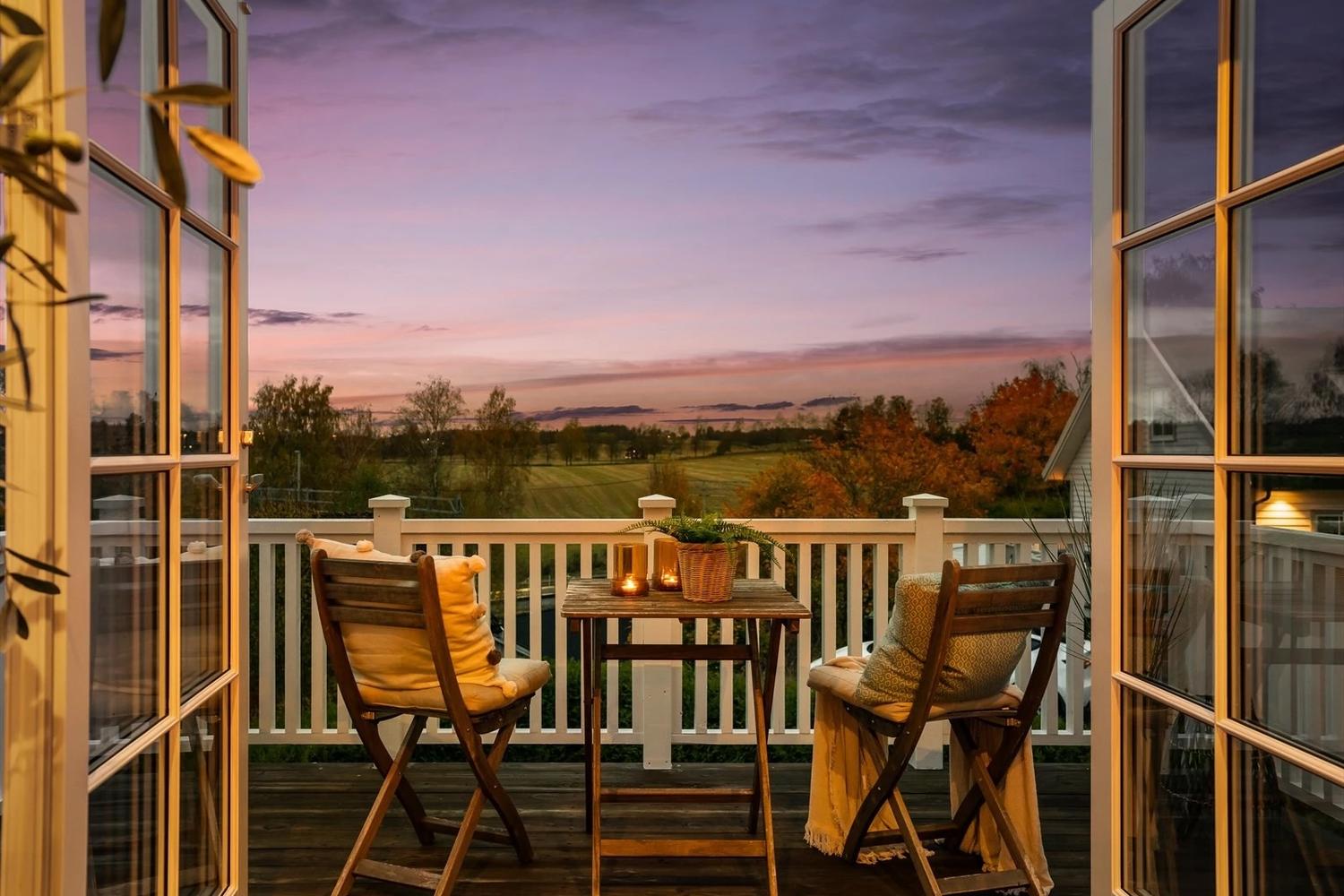 Terrasse med to stoler og et bord, sett innenifra.