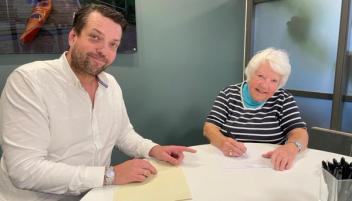 Eiendomsmegler og kunde sitter rundt et bord på et møterom. Foto.