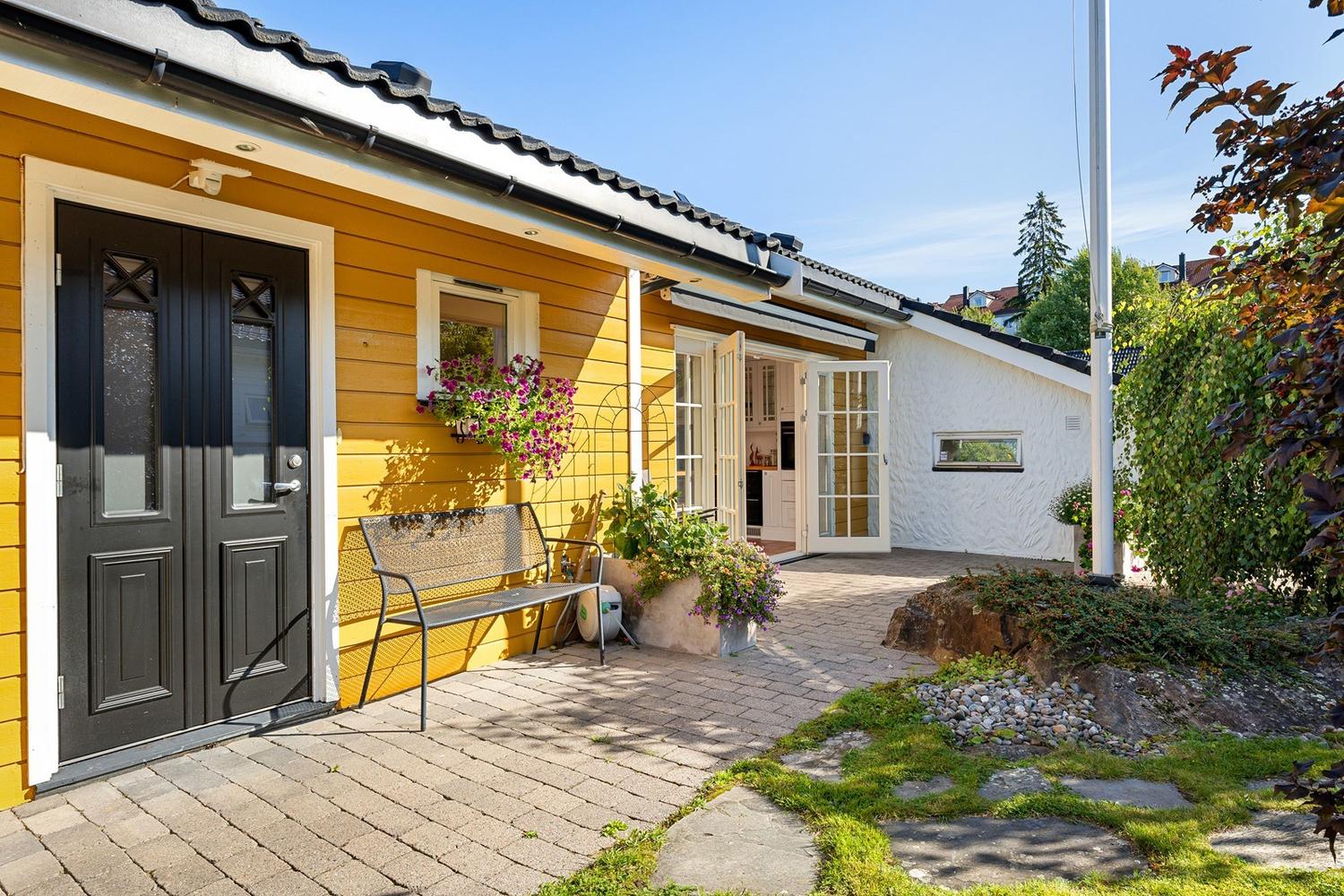 Koselig, gul enebolig med svart inngangsdør og hvite lister på Tårnåsen.