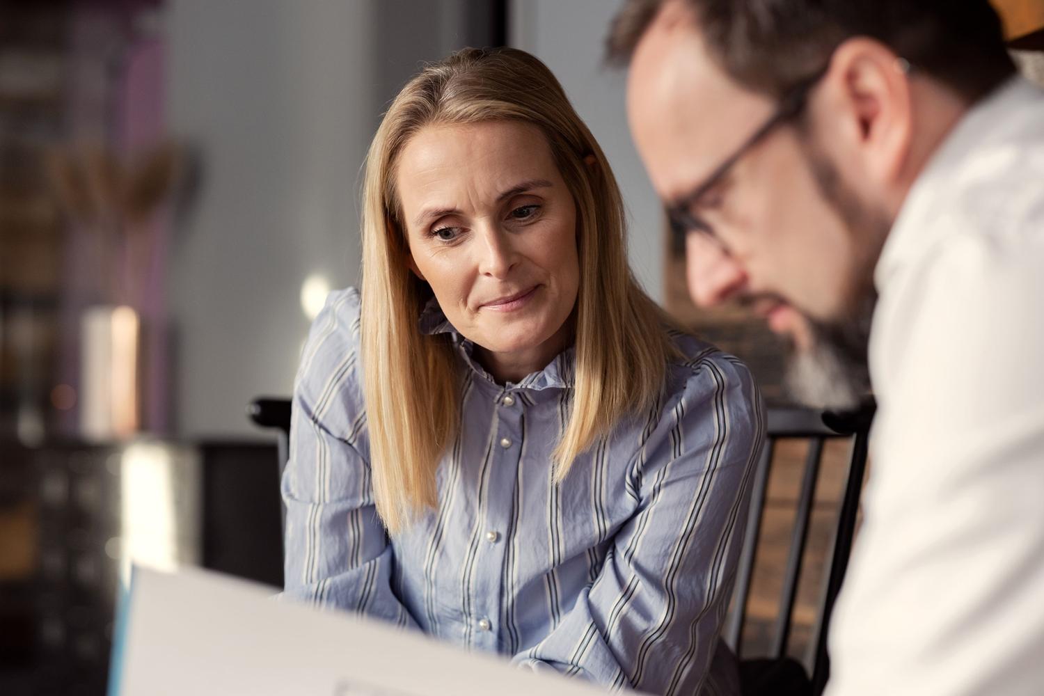 To eiendomsmeglere som studerer en salgsoppgave på et nytt boligbygg. Foto.