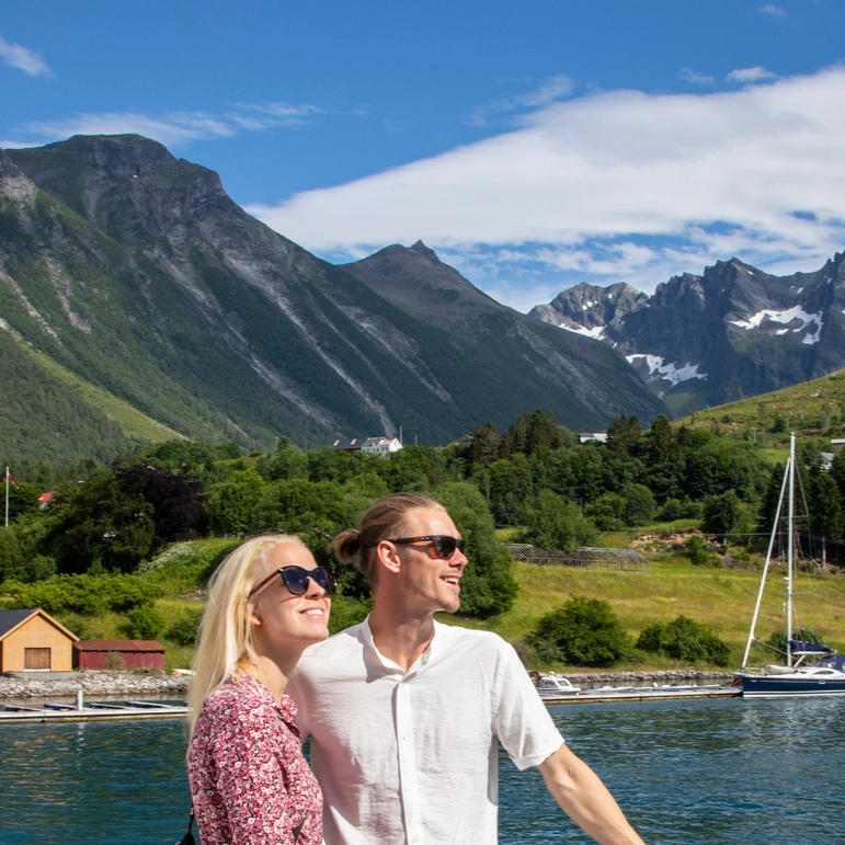 Romantic fjord cruise experience Hjørundfjord Norway Couple enjoying Hjørundfjord cruise from Ålesund with dramatic Sunnmøre Alps mountain backdrop