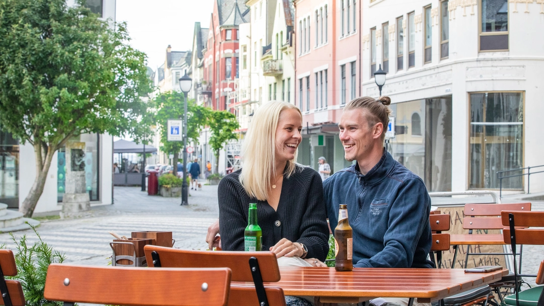 Café culture in Kongens gate, Ålesund Couple enjoying a drink at a café in Kongens gate, Ålesund. Experience local culture during your Ålesund holiday while surrounded by beautiful Art Nouveau buildings.