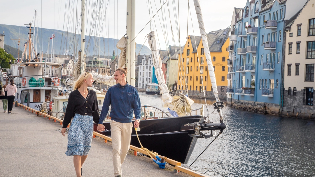 Ålesund harbor with Art Nouveau architecture Couple exploring Ålesund harbor with its iconic Art Nouveau architecture and boats. A perfect starting point for Ålesund tours and cruises to discover the surrounding fjords.