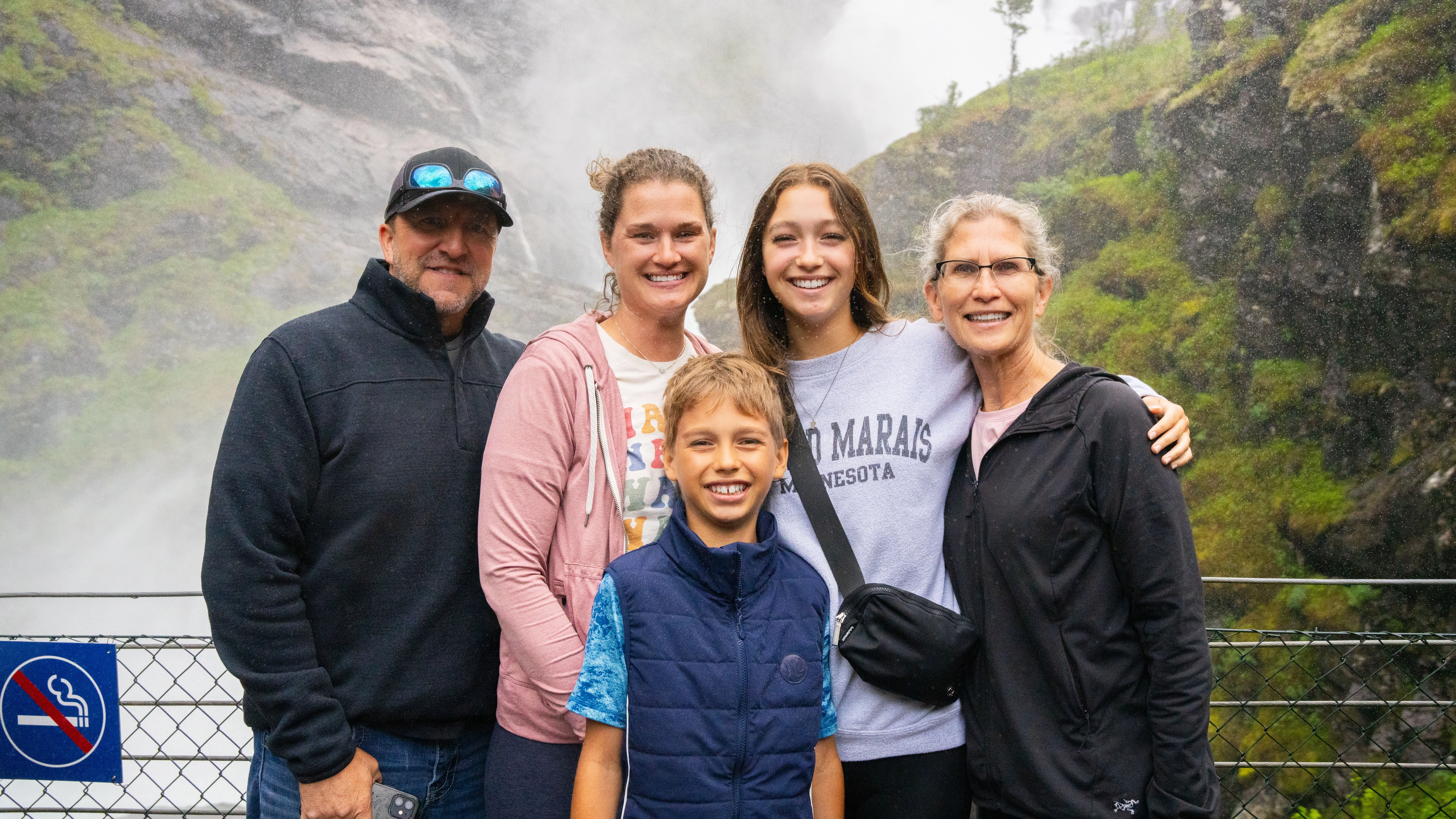 Family smiling in front of the Kjosfossen waterfall