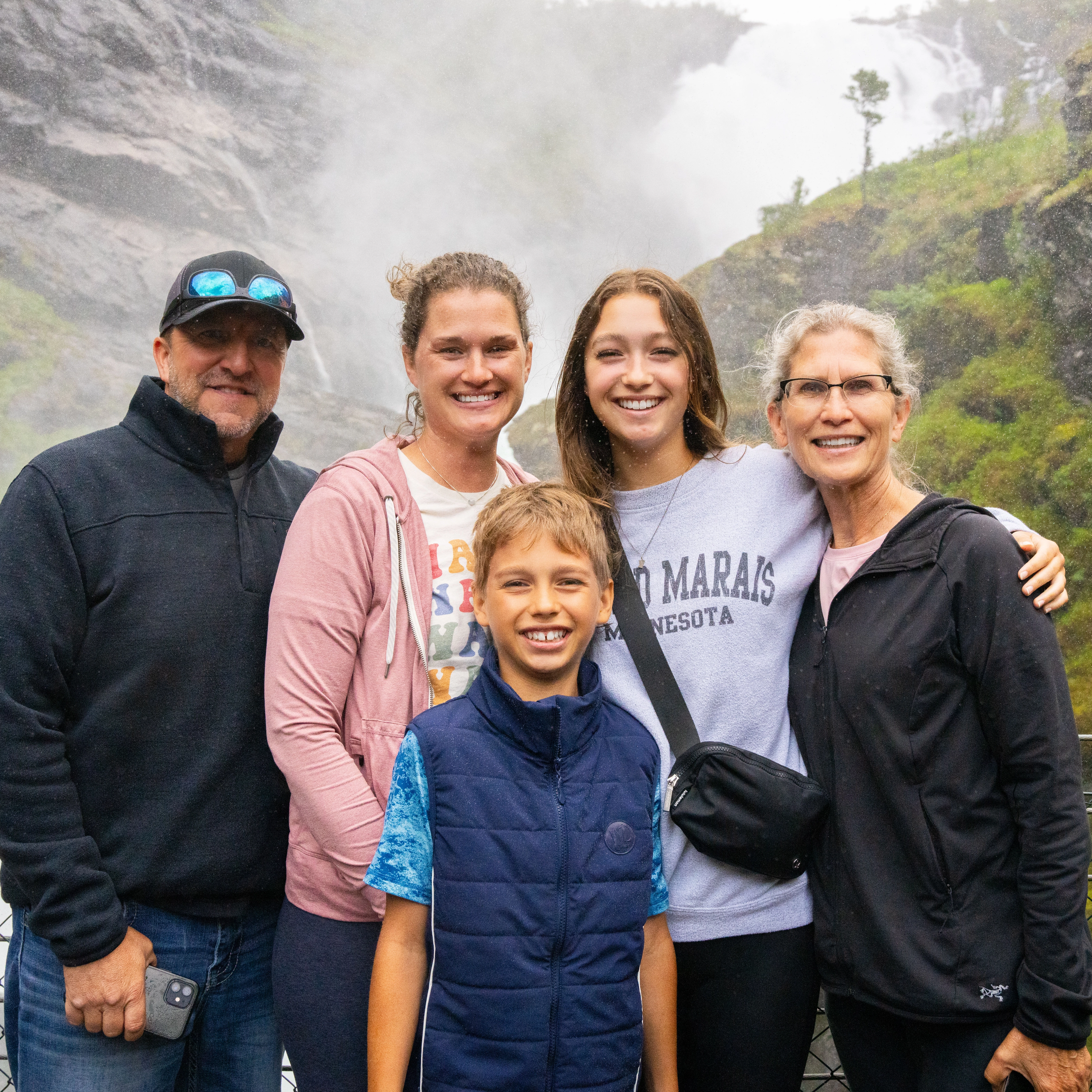 Family smiling in front of the Kjosfossen waterfall