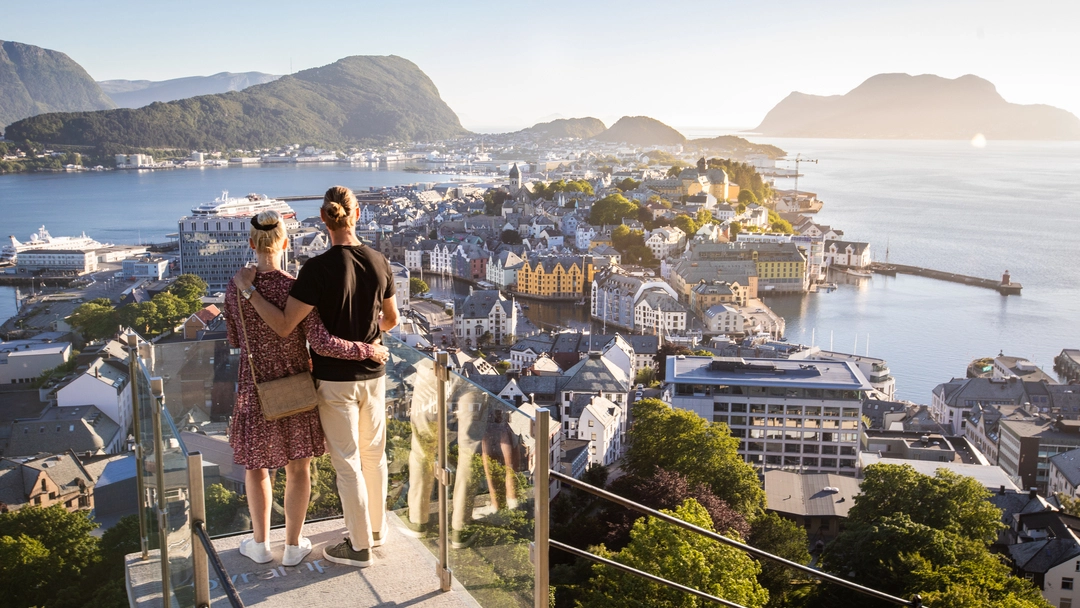 Panoramic view from Mount Aksla in Ålesund Couple enjoying the panoramic view from Aksla viewpoint in Ålesund, Norway. One of the most popular Ålesund excursions offering spectacular views of the Art Nouveau city, archipelago and Sunnmøre Alps.