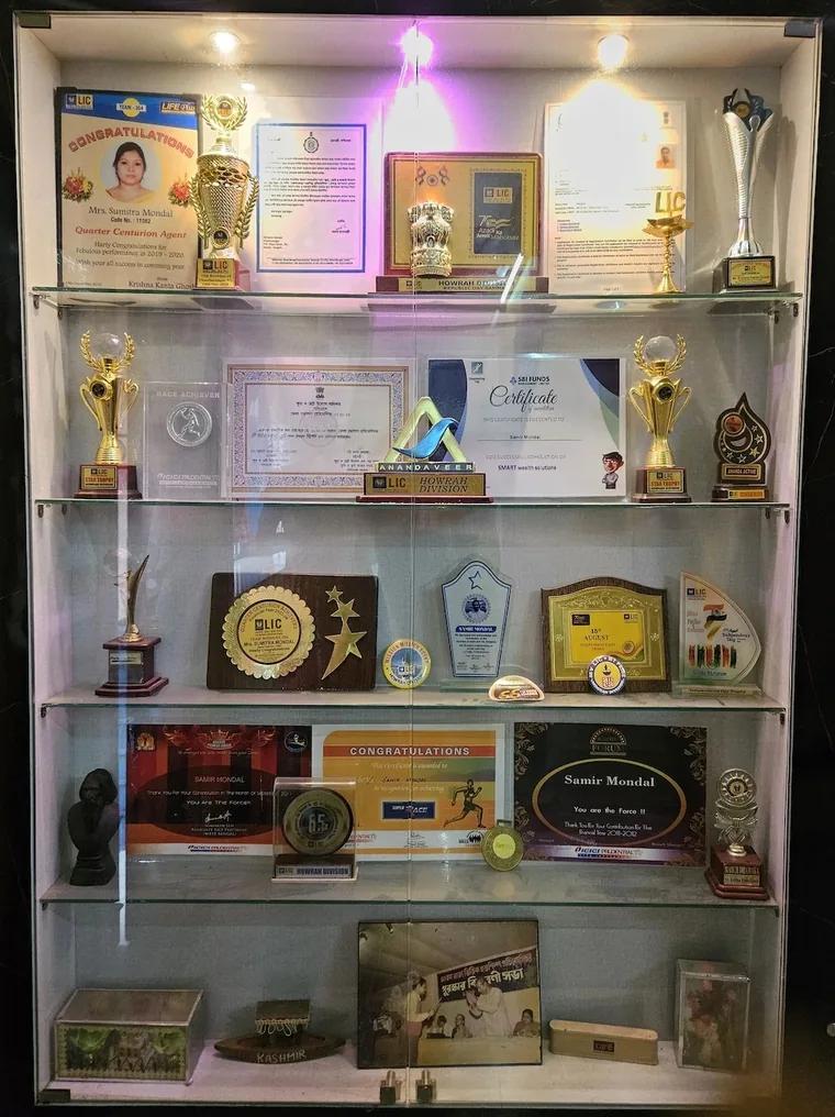A display cabinet of LIC and mutual fund trophies, plaques and certificates earned over the years