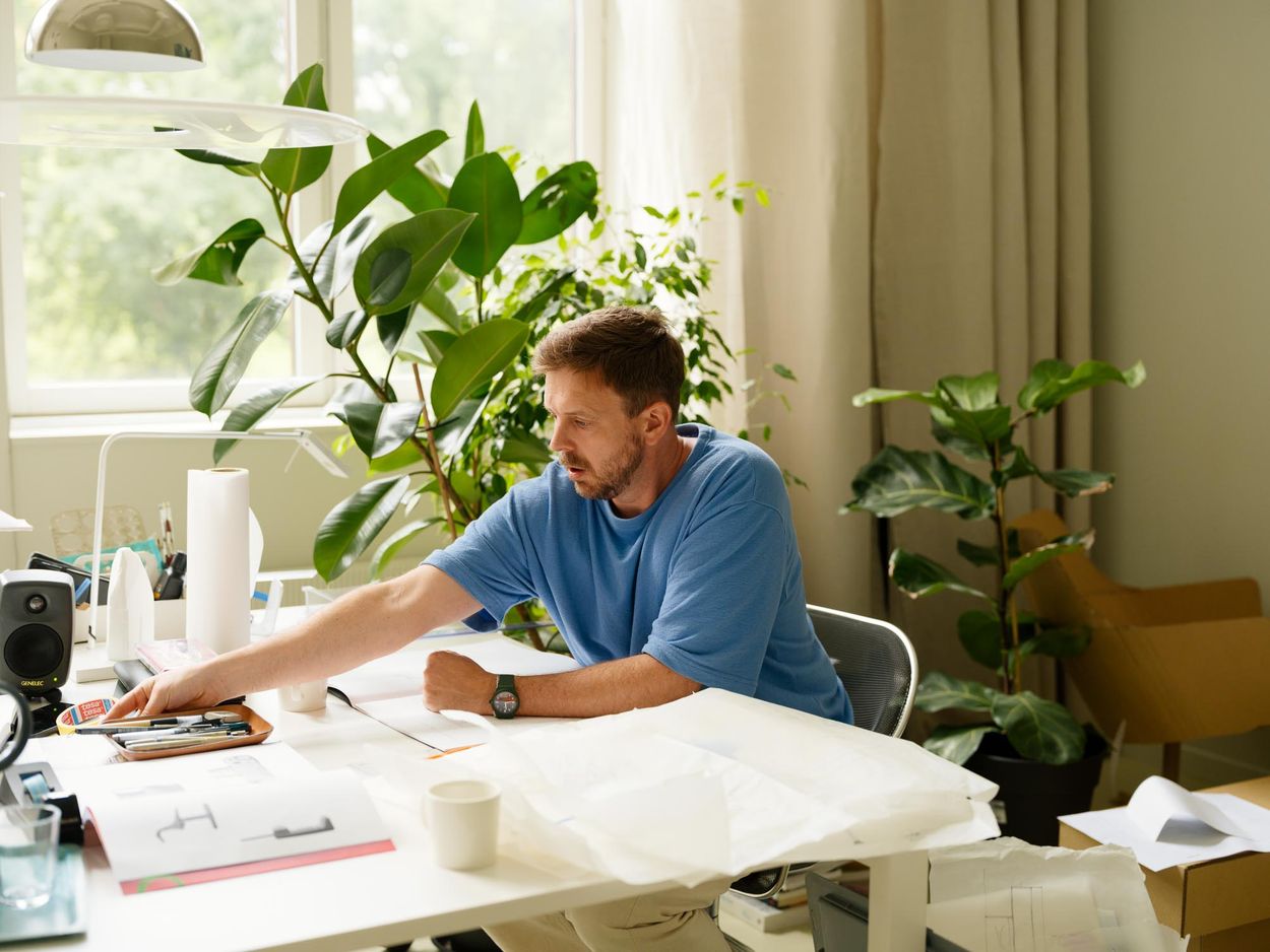 Jonas Stokke sitting by his desk, reaching for something