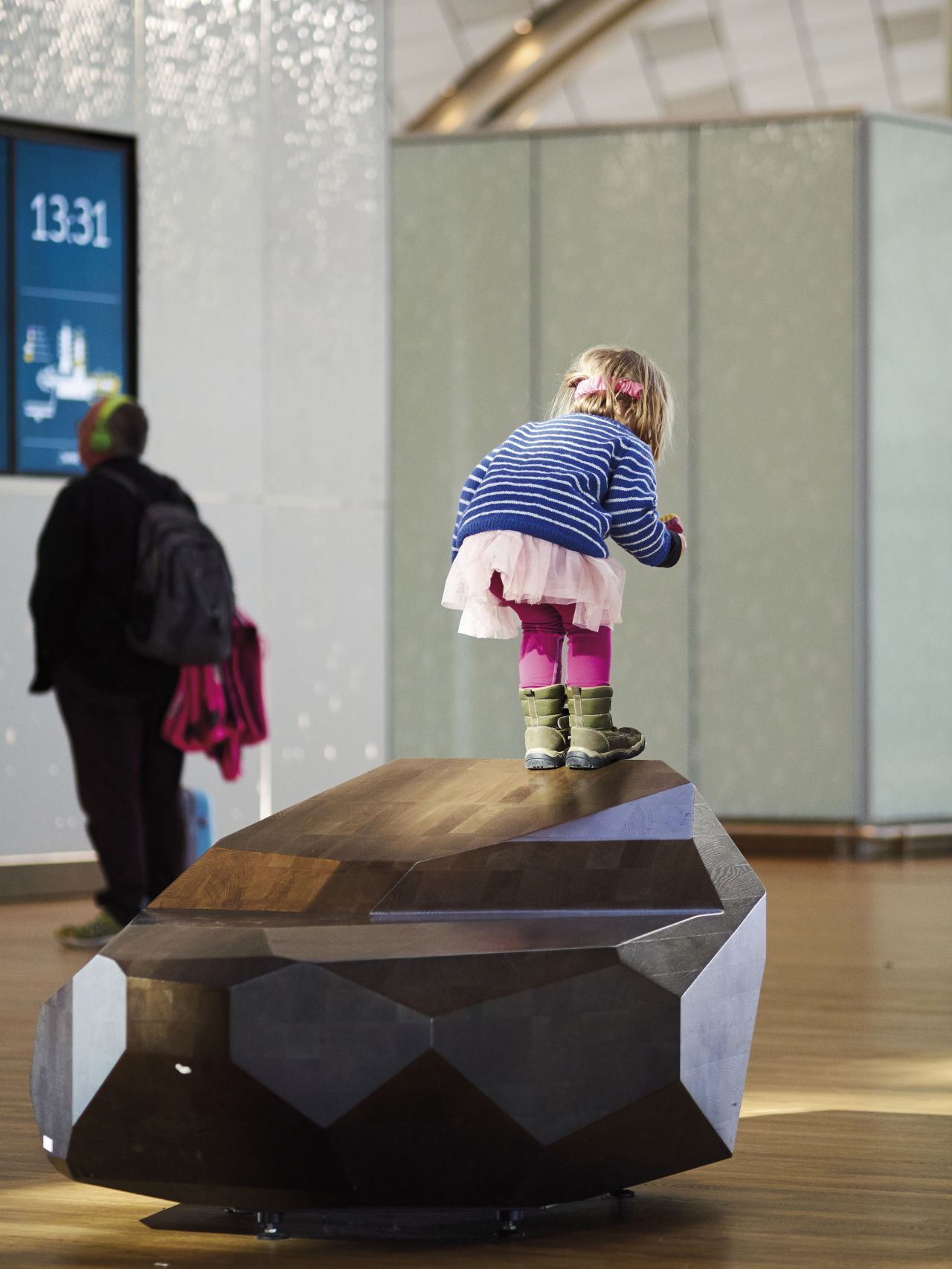 Gateway to Scandinavia designed by Jonas Stokke, wooden benches inspired by stones, alternative seating for an airport, child playing