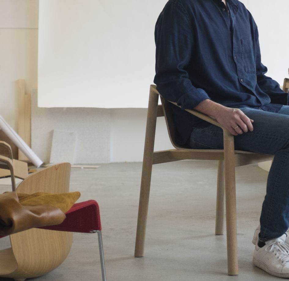 partial view of man sitting in wooden chair by Stokke in open designers studio