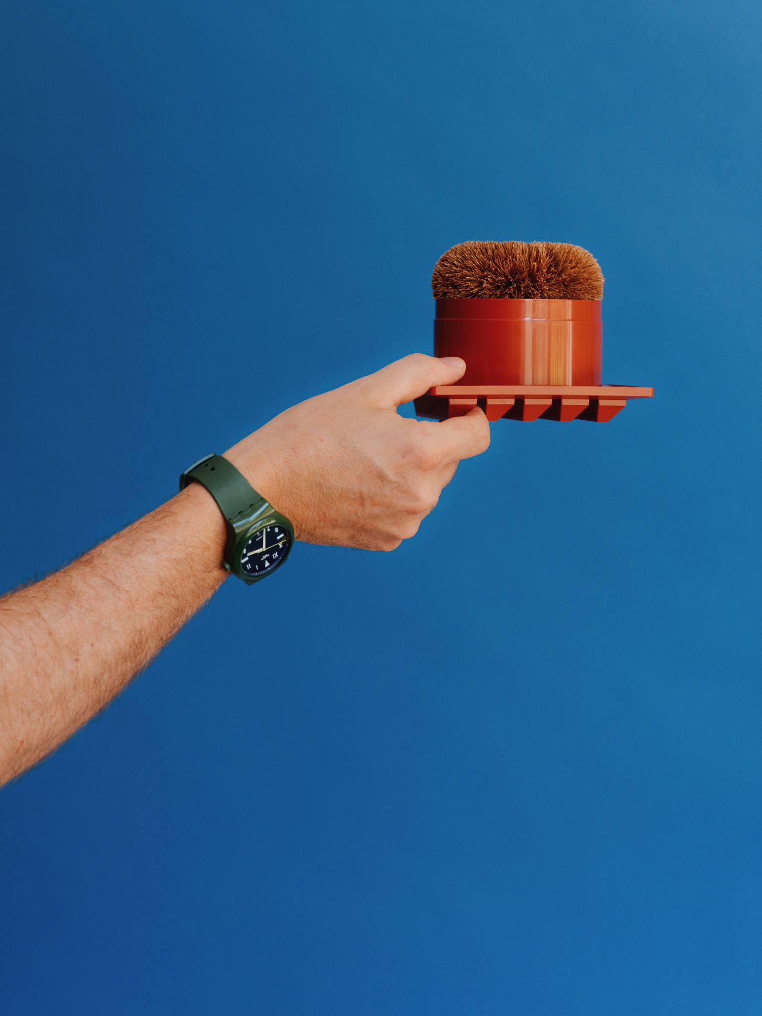 hand with green watch holding a scent disperser