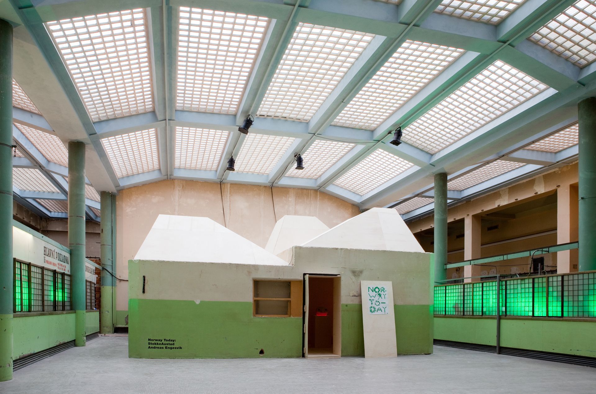 inside of exhibition space with green light. Wooden walls and pedestals