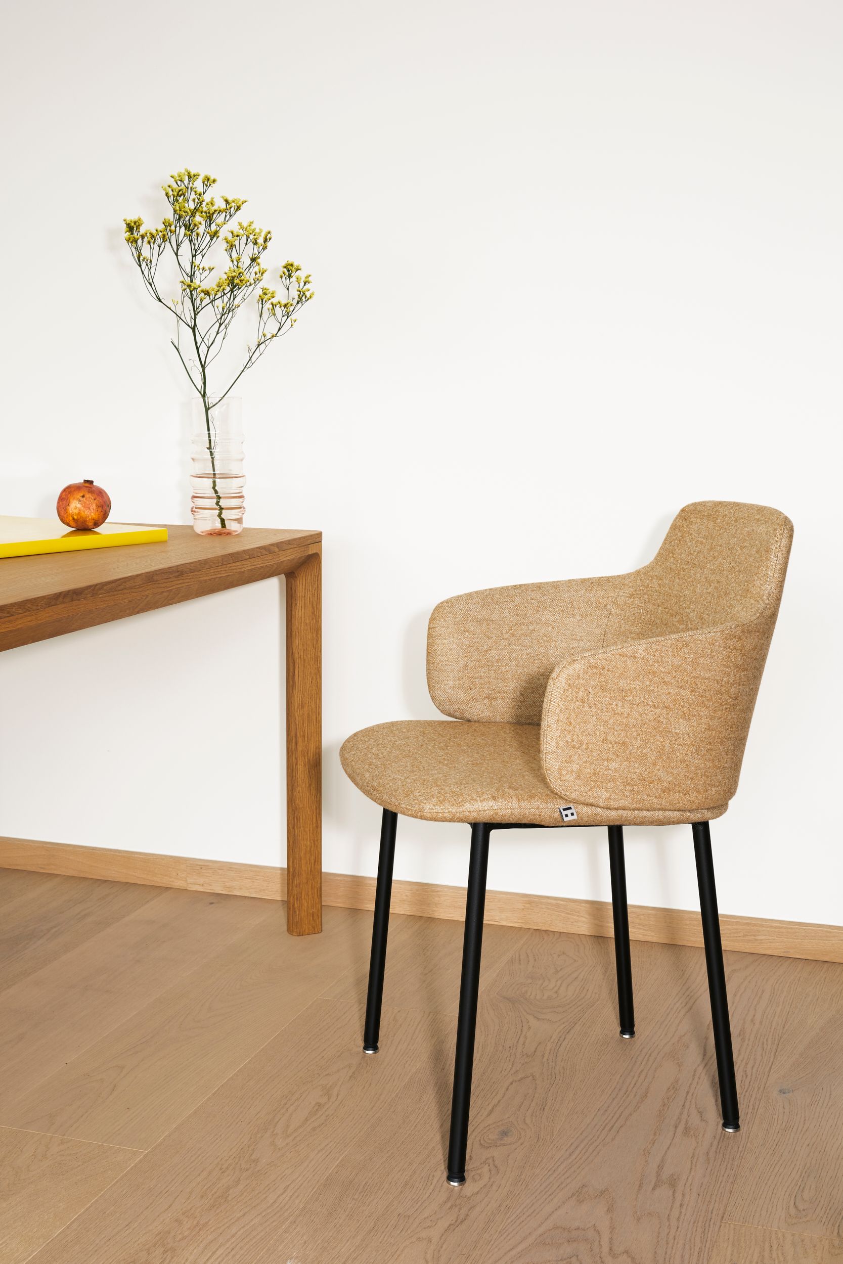 Ada Chair designed by Jonas Stokke for LK Hjelle, with four black legs, from the side, standing by a table with a flower and an onion (?).