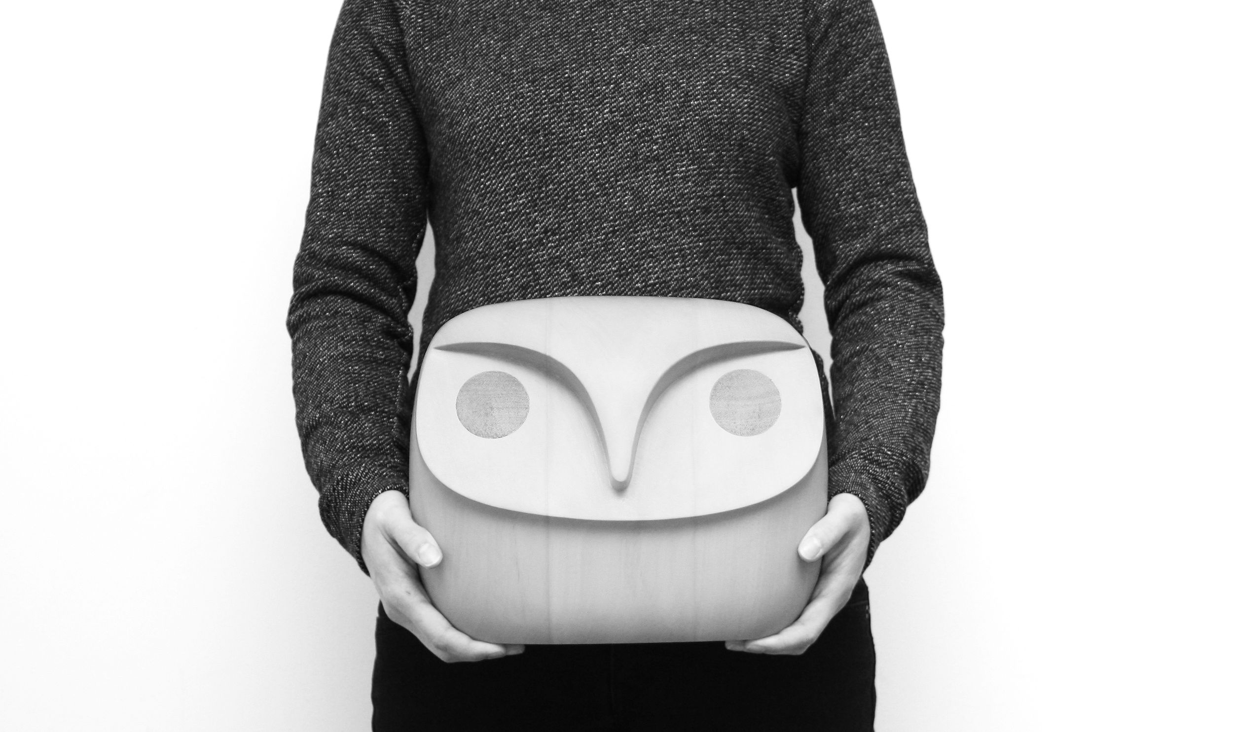 black and white image of person holding a large wooden owl