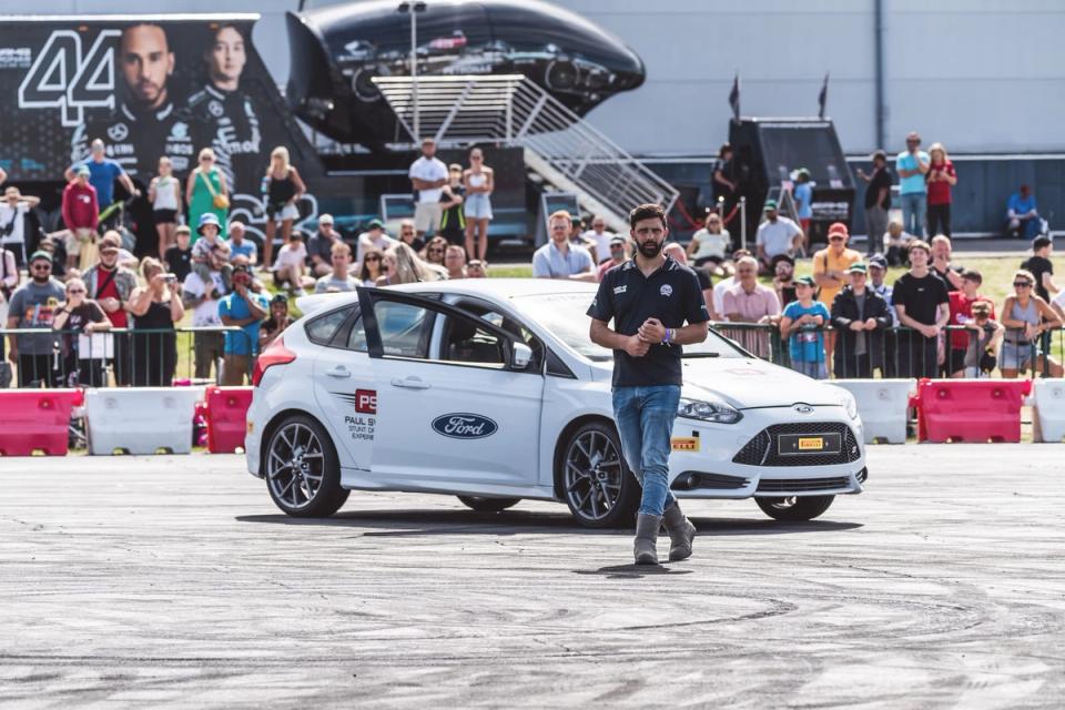 Sam walking away from a white Ford Focus RS in front of a crowd at the British Motor Show