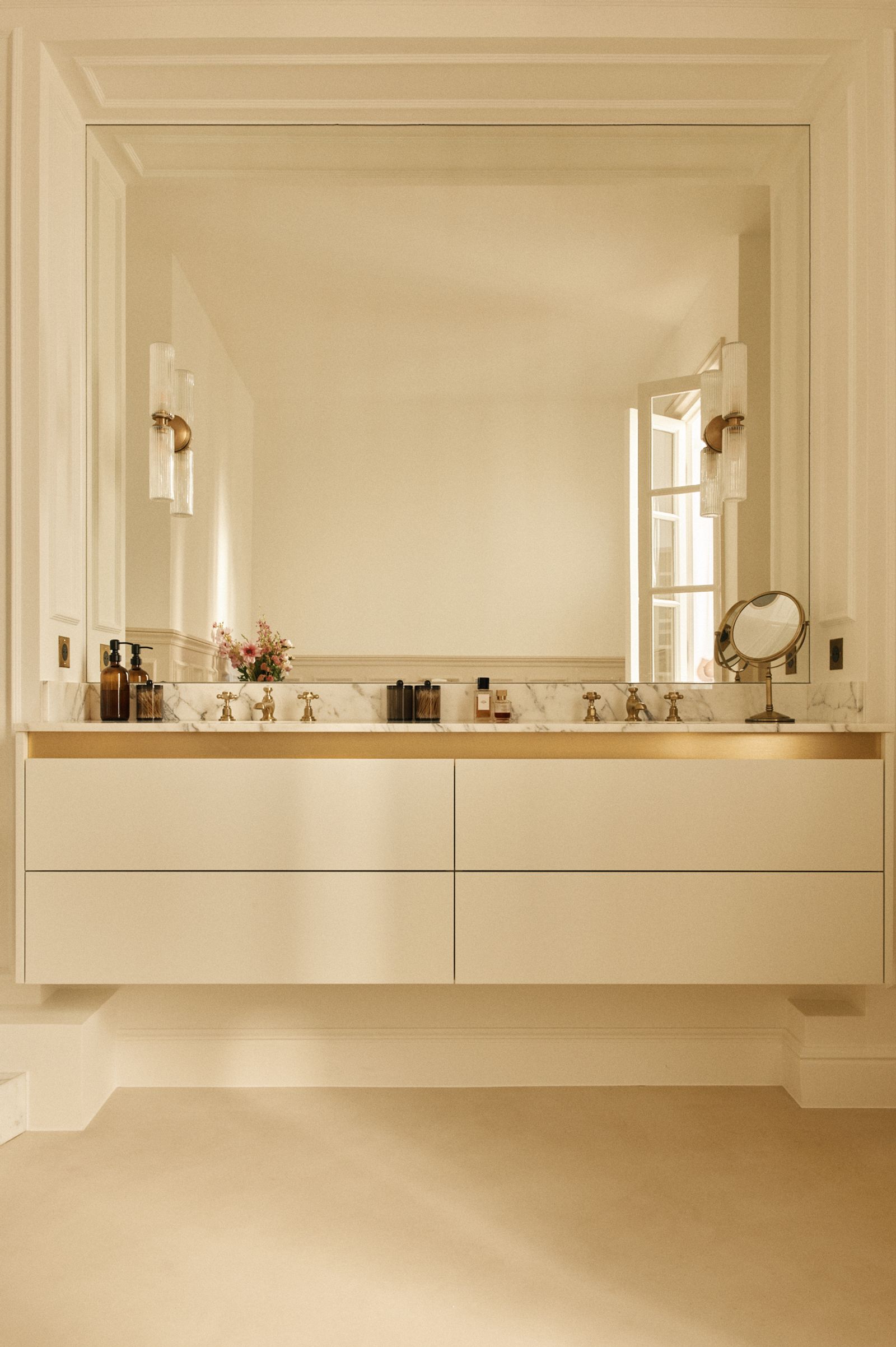 Plan vasque double et dosseret en marbre blanc veiné, meuble suspendu laqué crème, miroir encadré de moulures