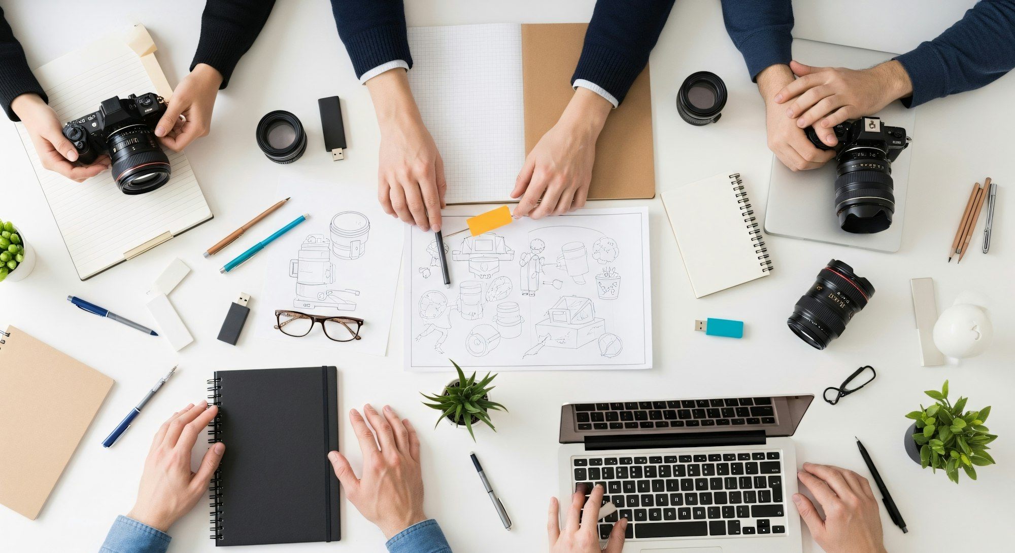 Hands sketching wireframes around a laptop
