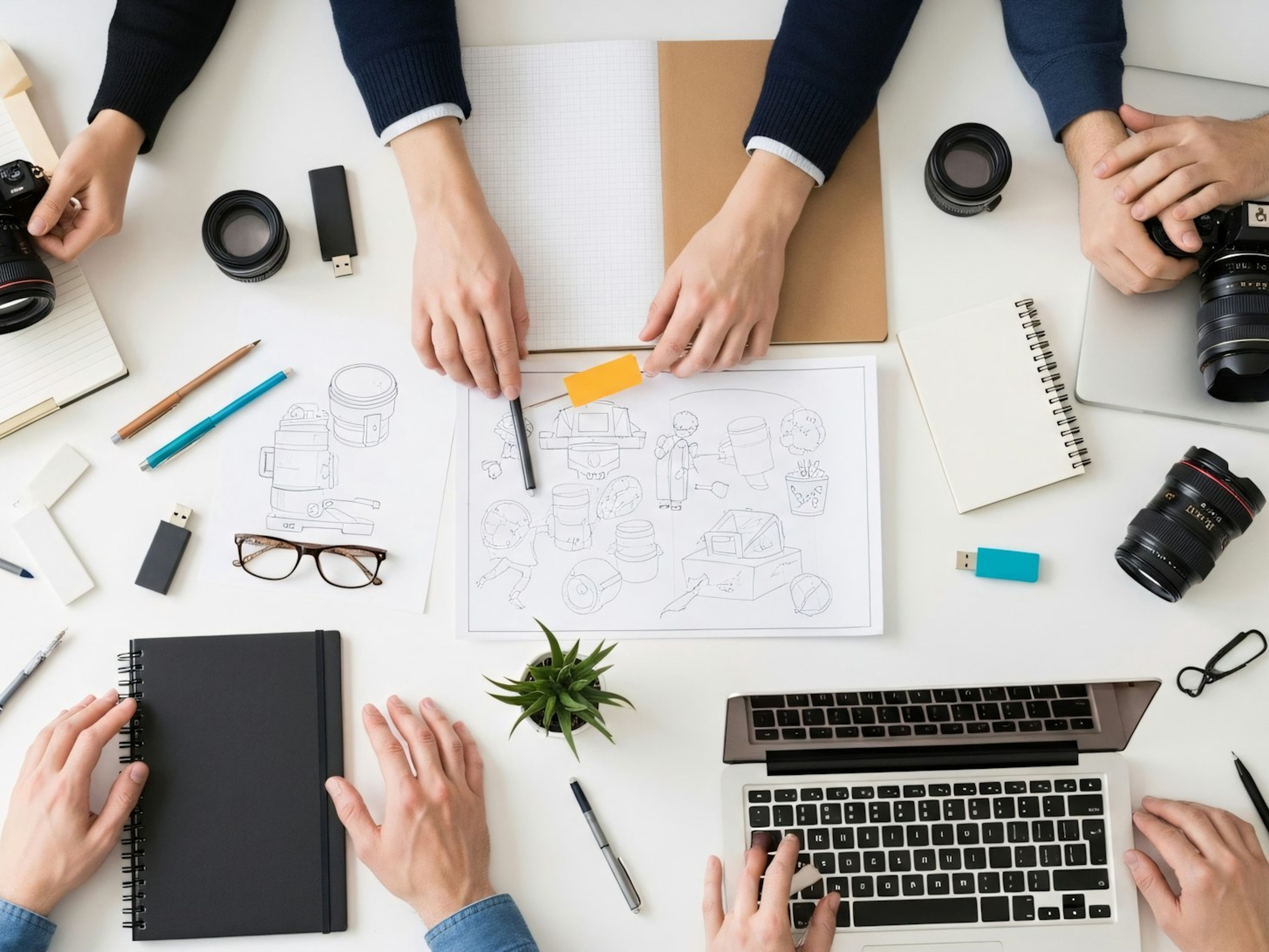 Hands sketching wireframes around a laptop